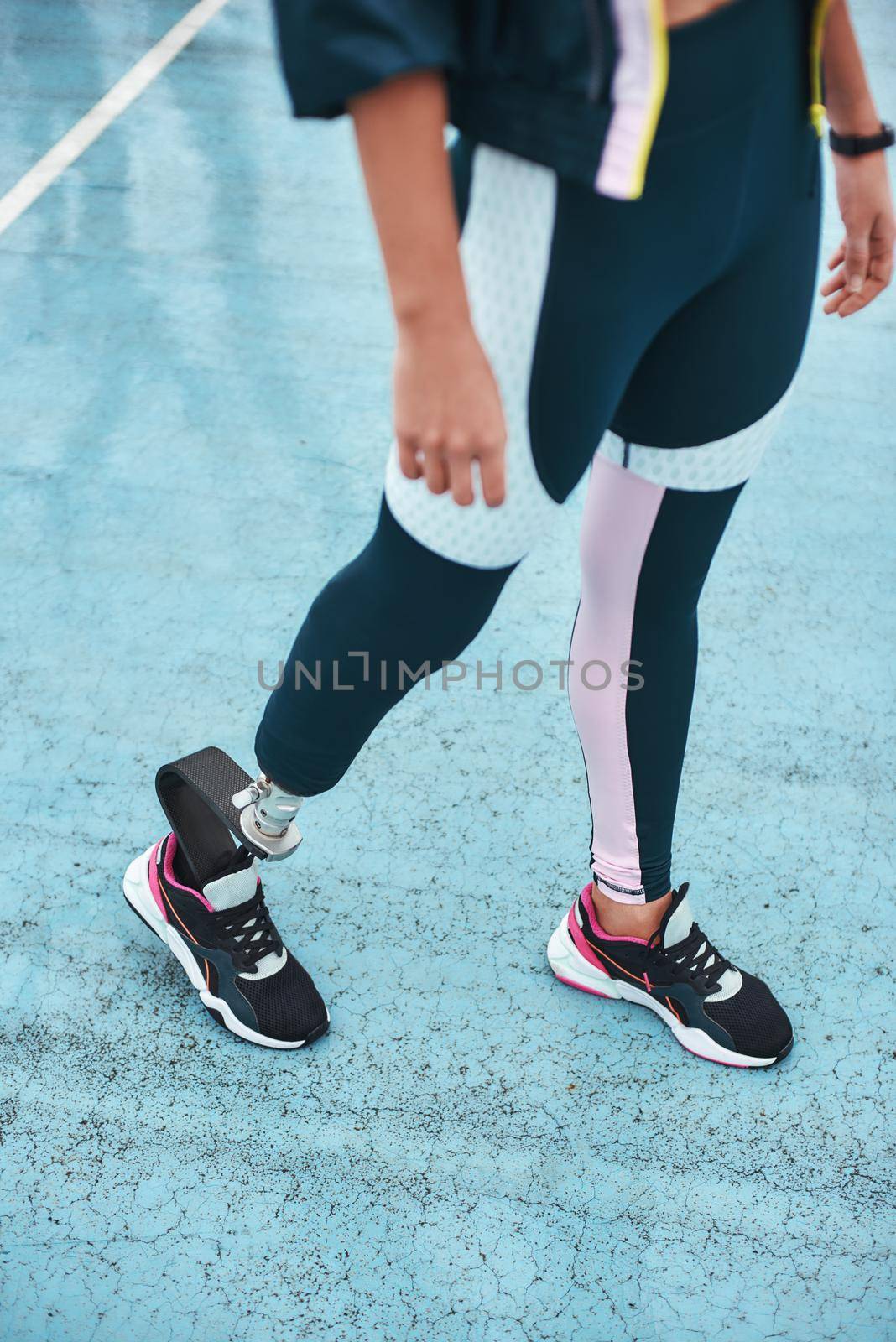 Just keep running. Cropped image of disabled woman in sportswear with bionic leg standing on stadium while doing her morning workout. by friendsstock