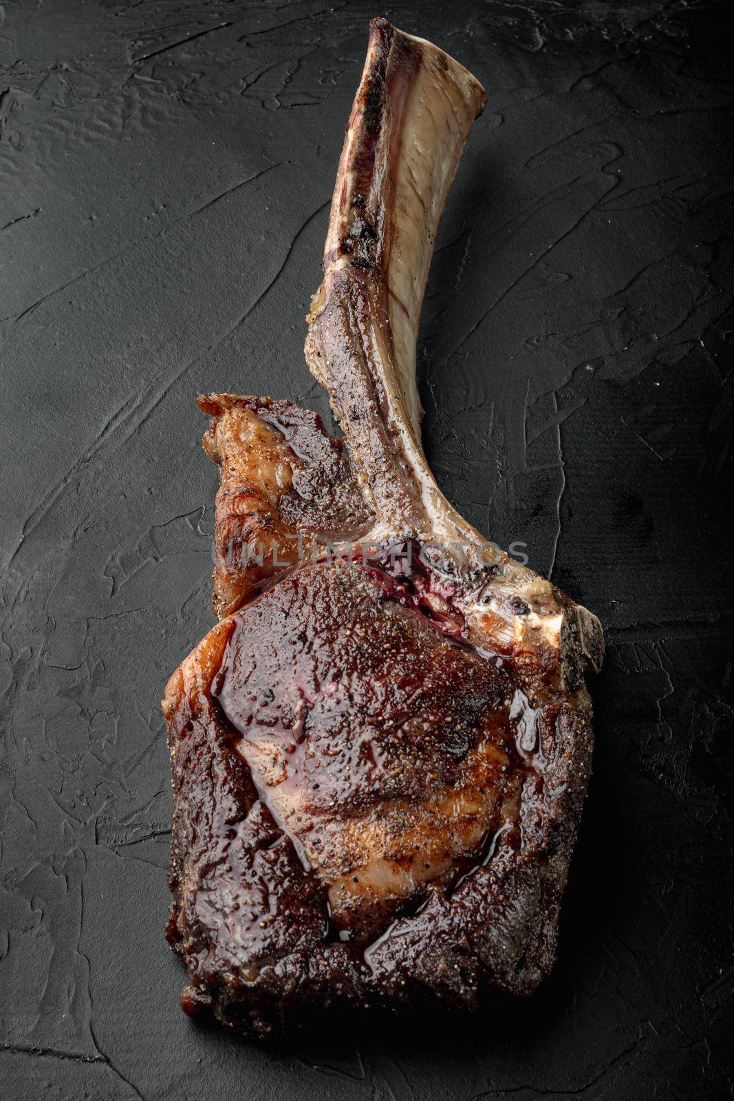 Juicy steak grilled on the bone tomahawk marbled beef set, on black stone background