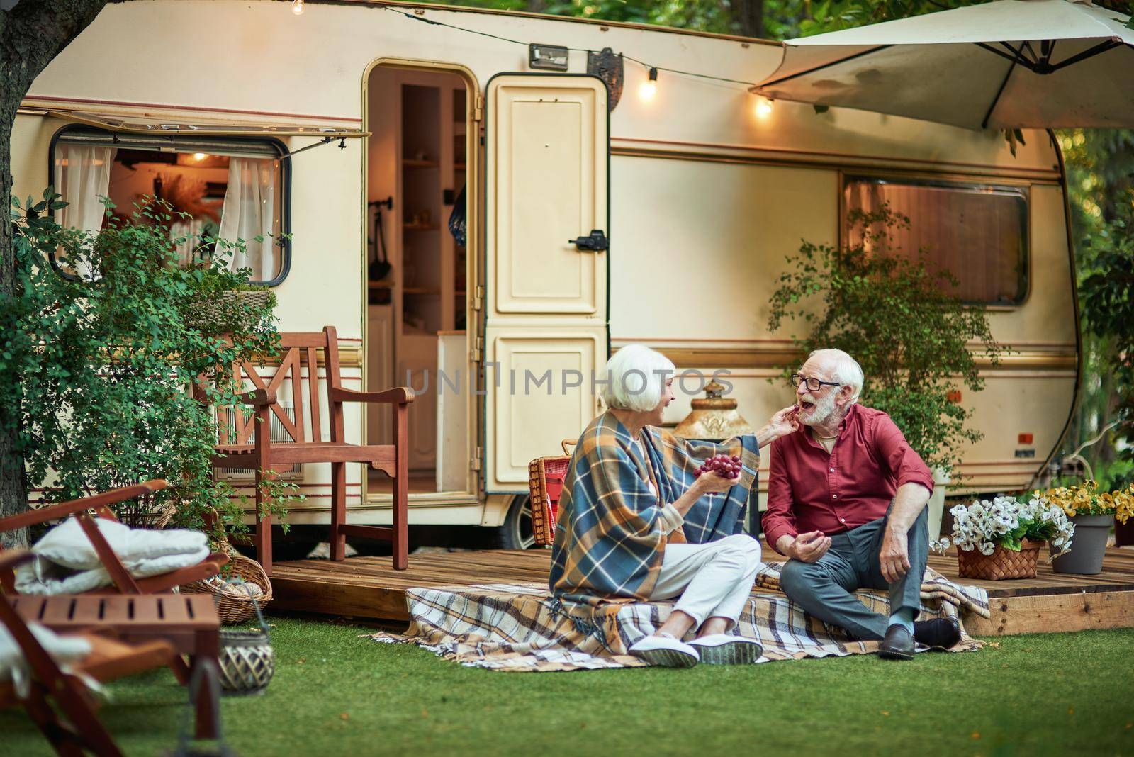 Happy senior man and woman looking each other and enjoying rest near their motorhome. Travel concept. Copy space