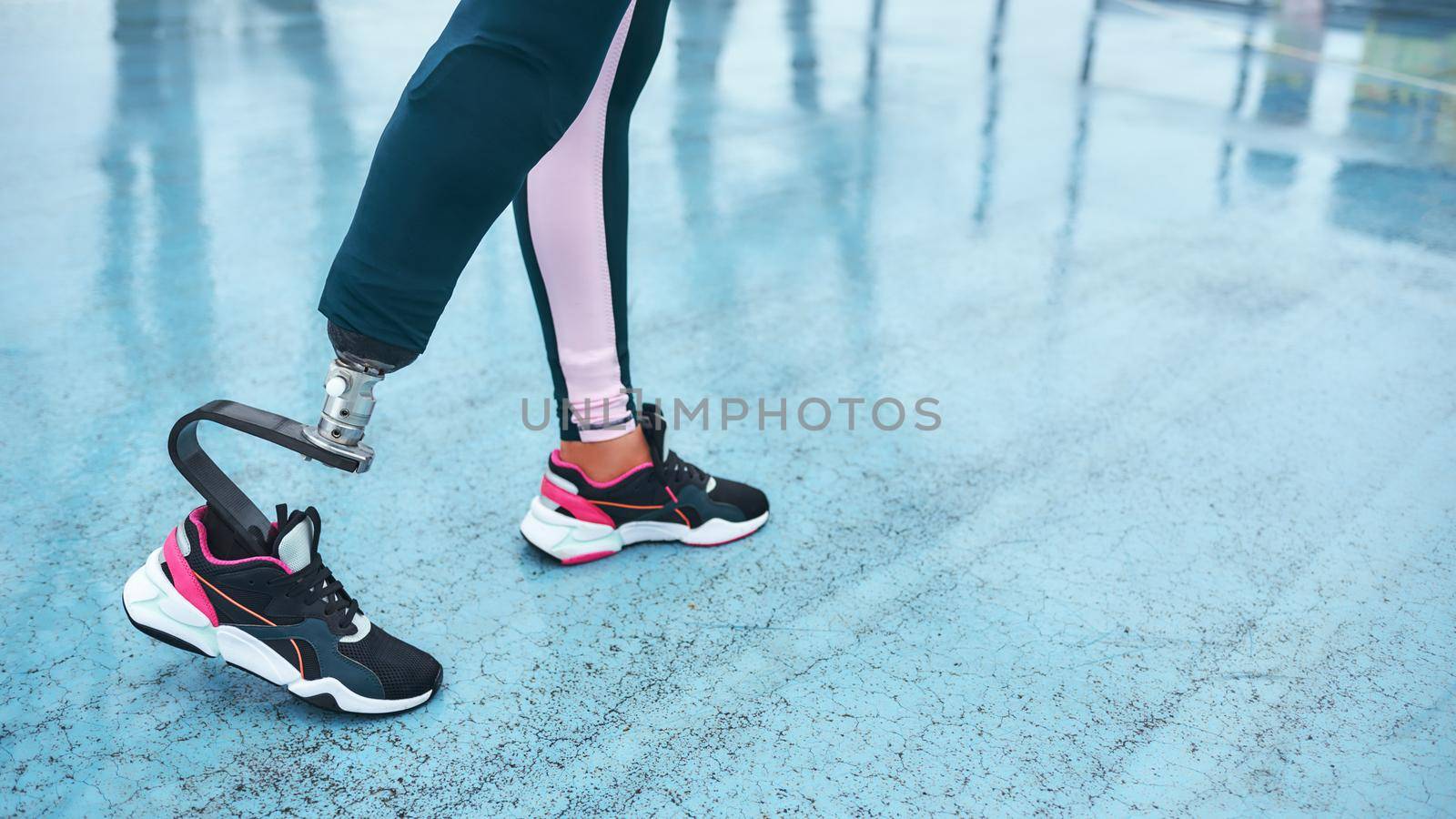 Wake up and workout. Cropped image of disabled athlete woman with prosthetic leg standing on stadium by friendsstock