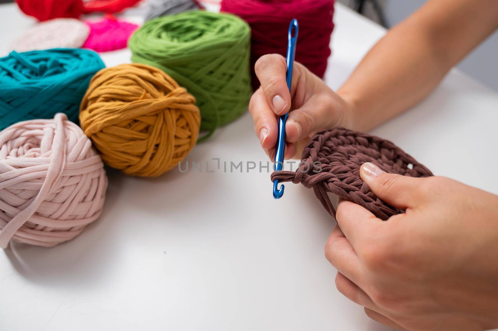 Close-up of a woman crocheting a basket of cotton yarn