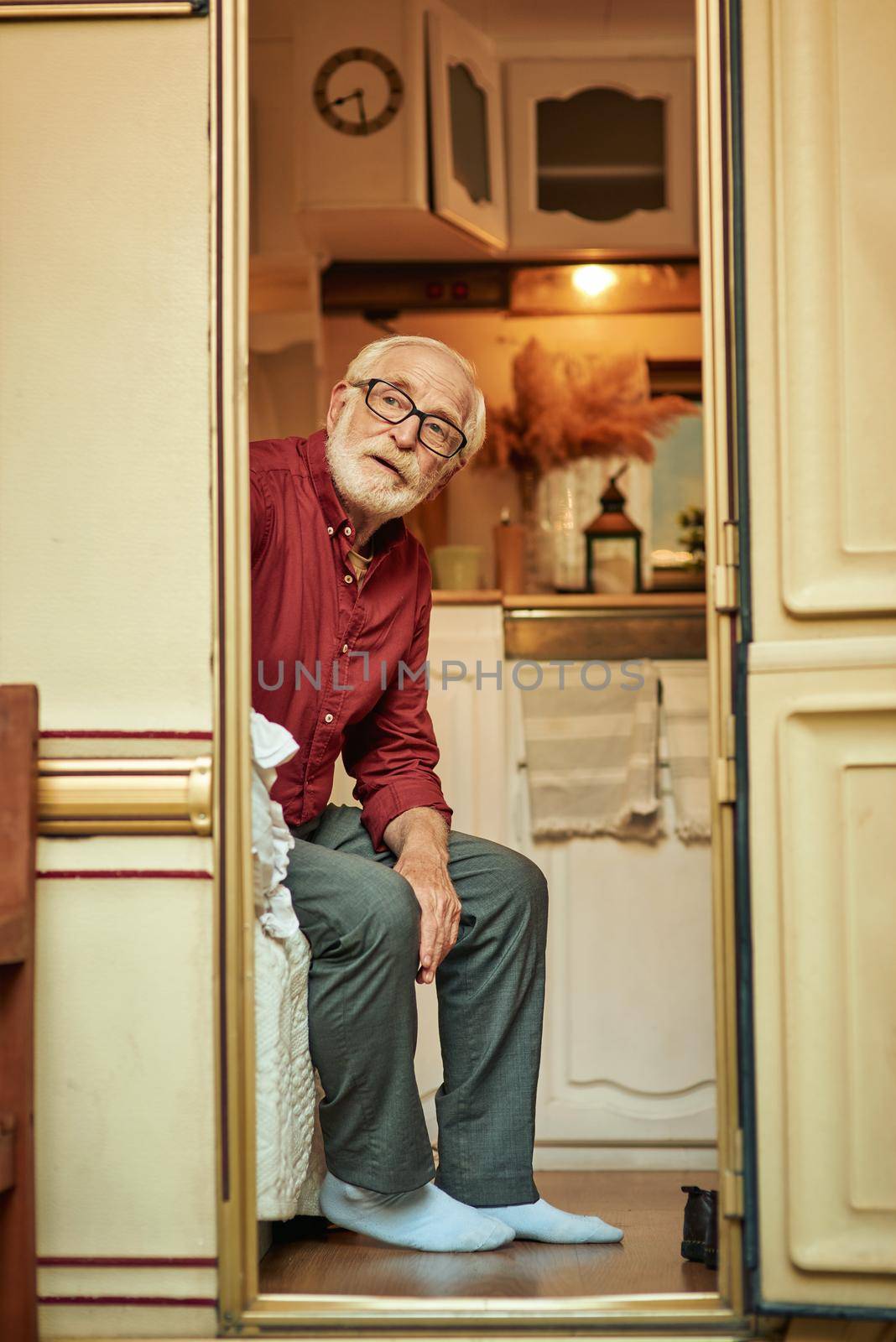 Senior unshoed male sitting on sofa in his motorhome by friendsstock