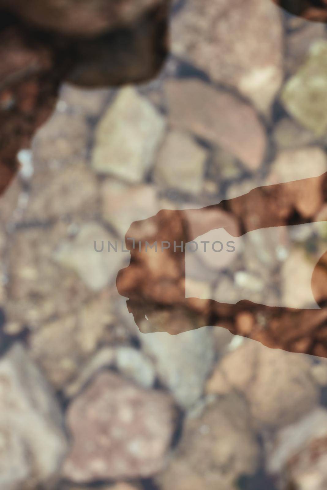 Shadow of the person holding photocamera. Reflection on the water with stones. Nature concept by friendsstock