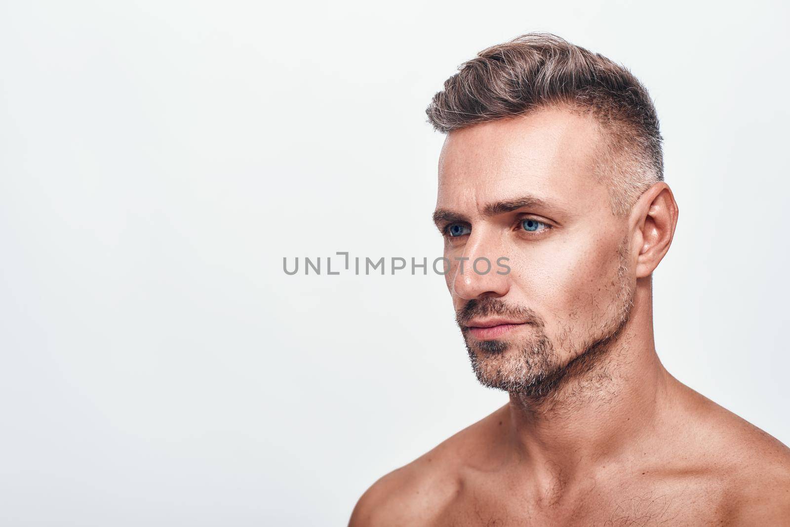 I need to shave. Side view of handsome and sexy man with a stubble looking aside while standing against grey background. Men beauty. Skin care