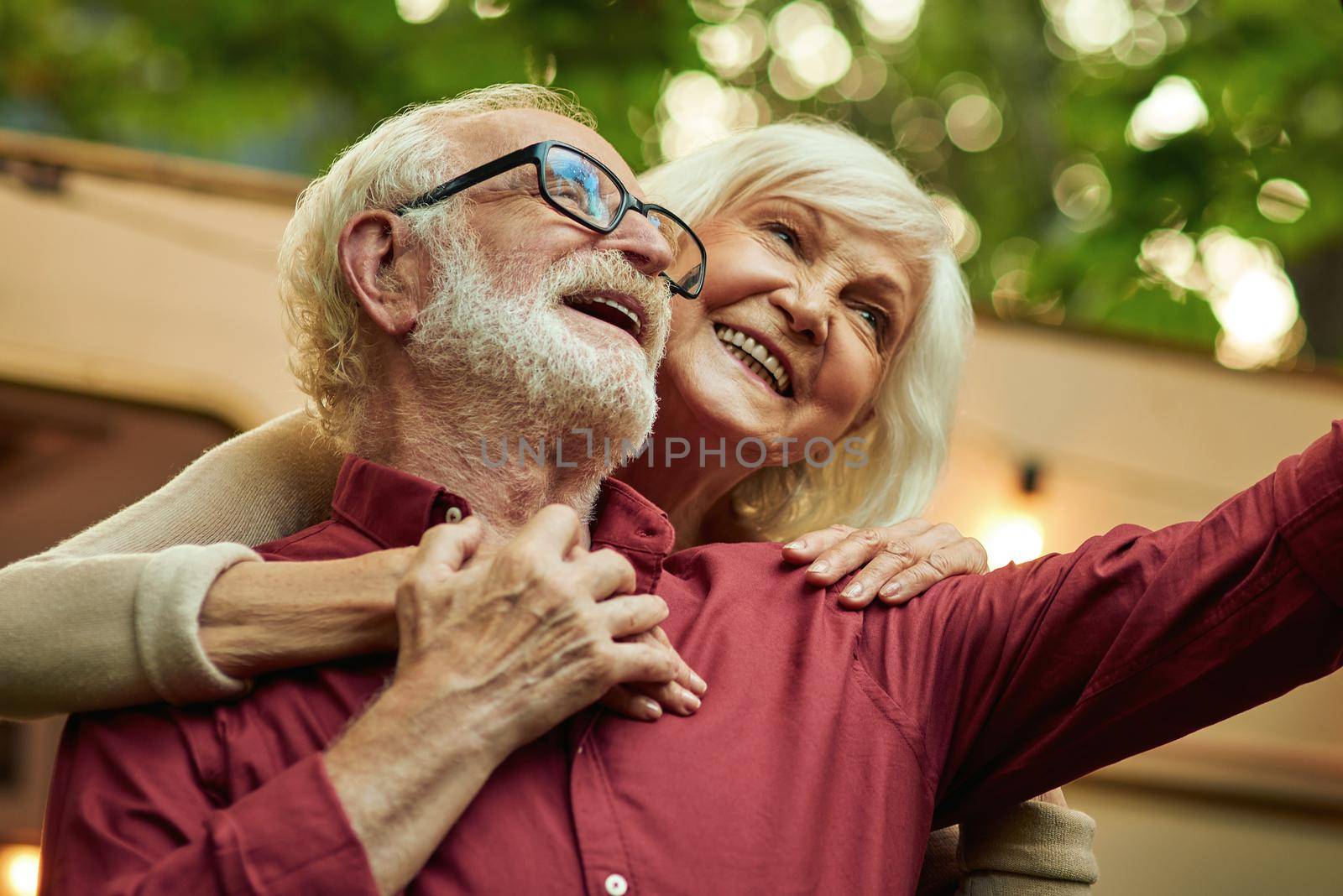 Smiling woman embracing her spouse and taking photo by friendsstock