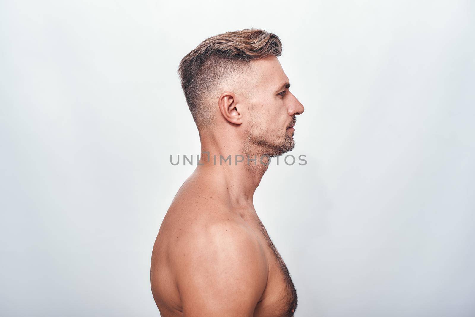 Handsome man. Side view of charming man with a stubble standing against grey background by friendsstock