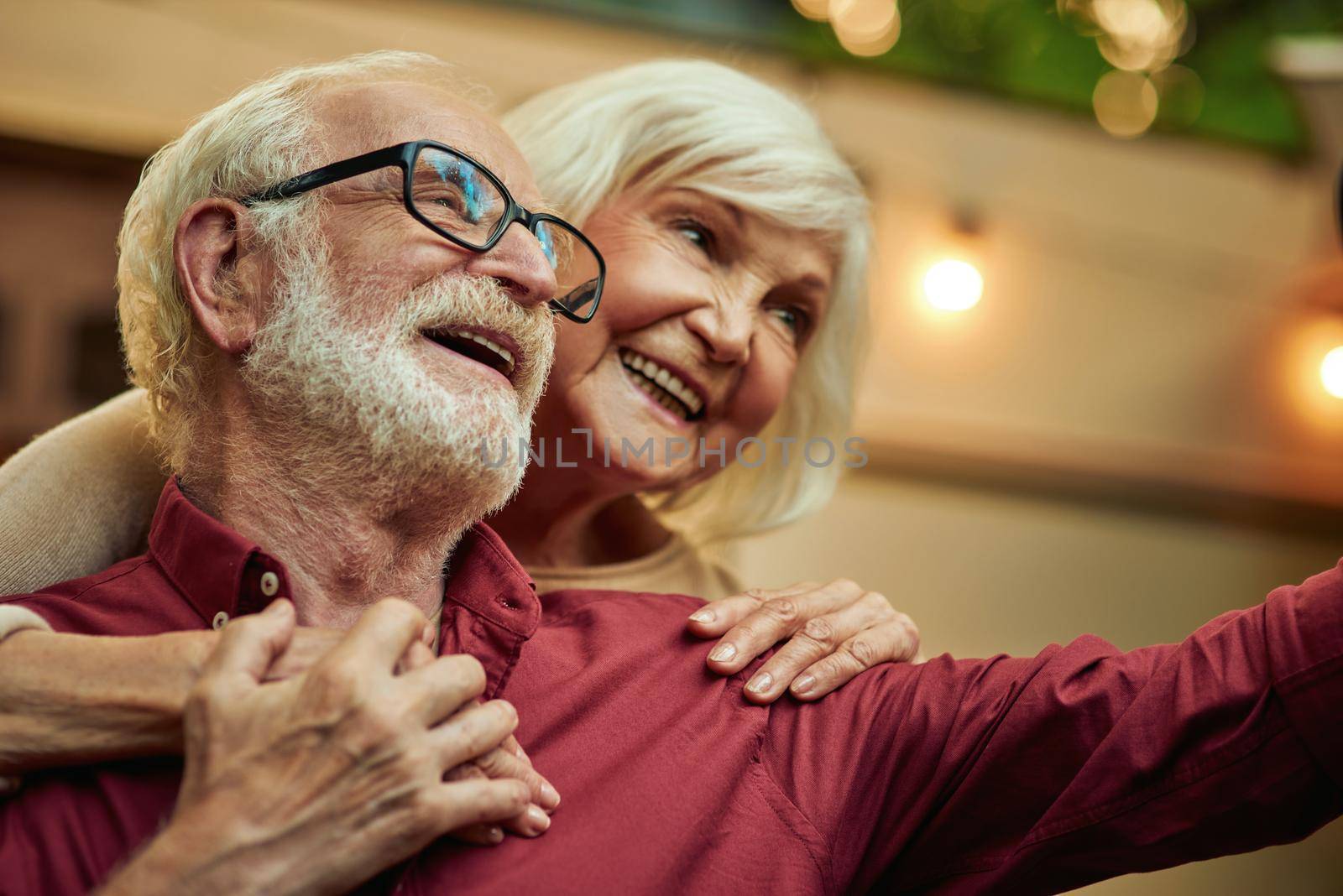 Smiling elderly married couple holding hands while making selfie together in the evening outdoors. Lifestyle concept