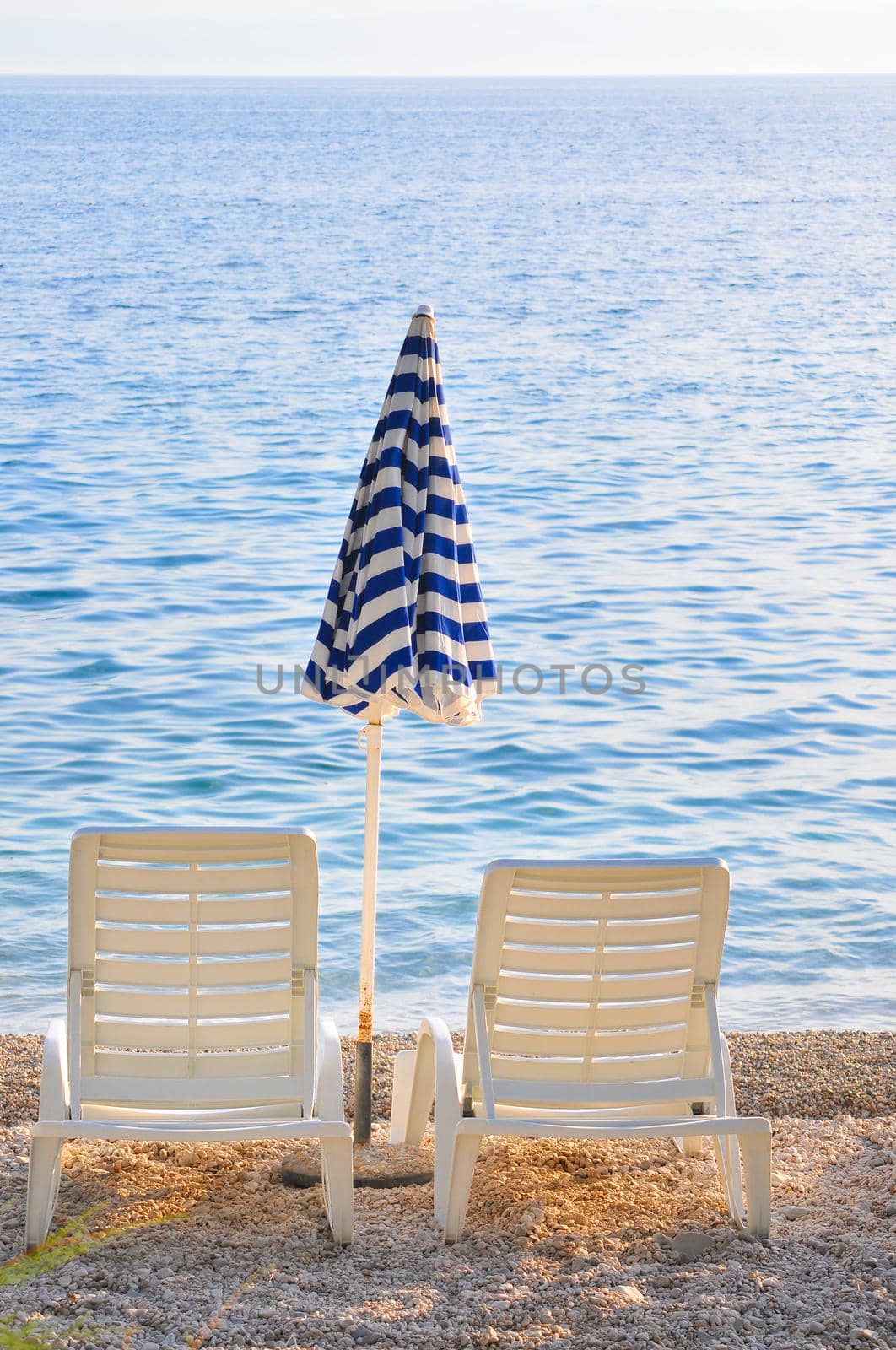 empty chairs on beach with umbrella