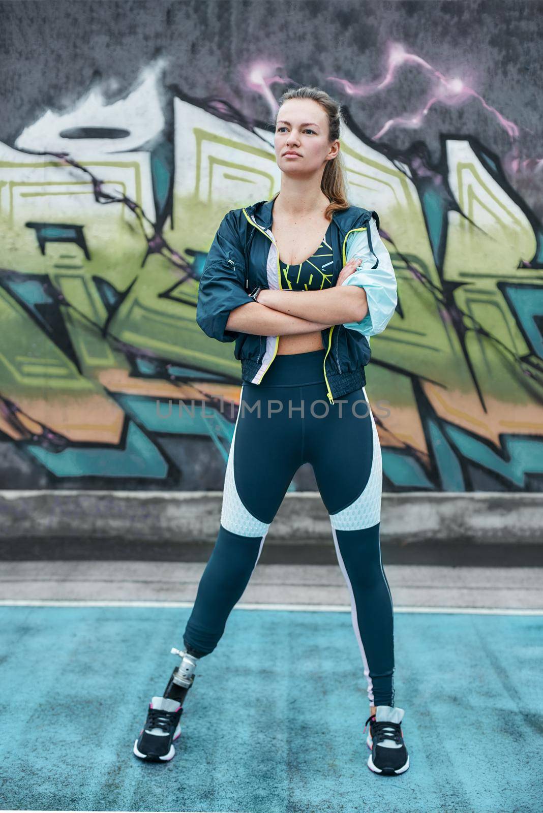 Never give up Disabled woman in sport wear with leg prosthesis standing outdoors and keeping arms crossed. by friendsstock