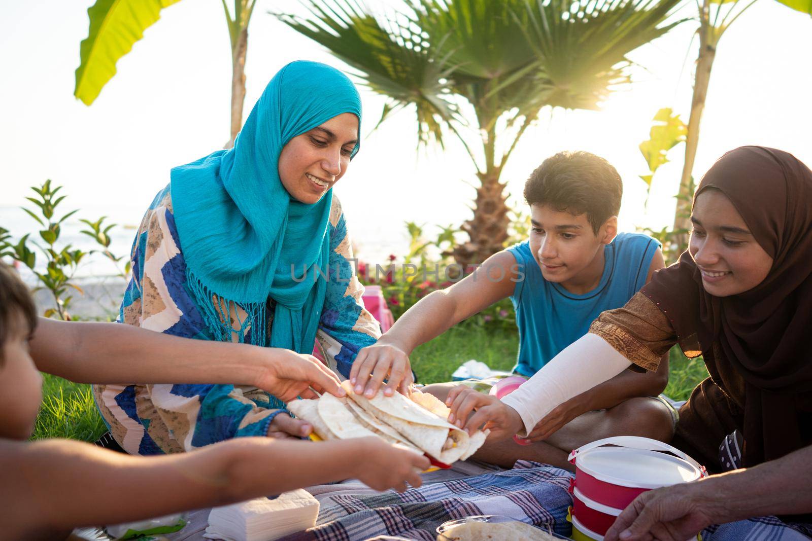 Happy family enjoying picnic on beach by Zurijeta