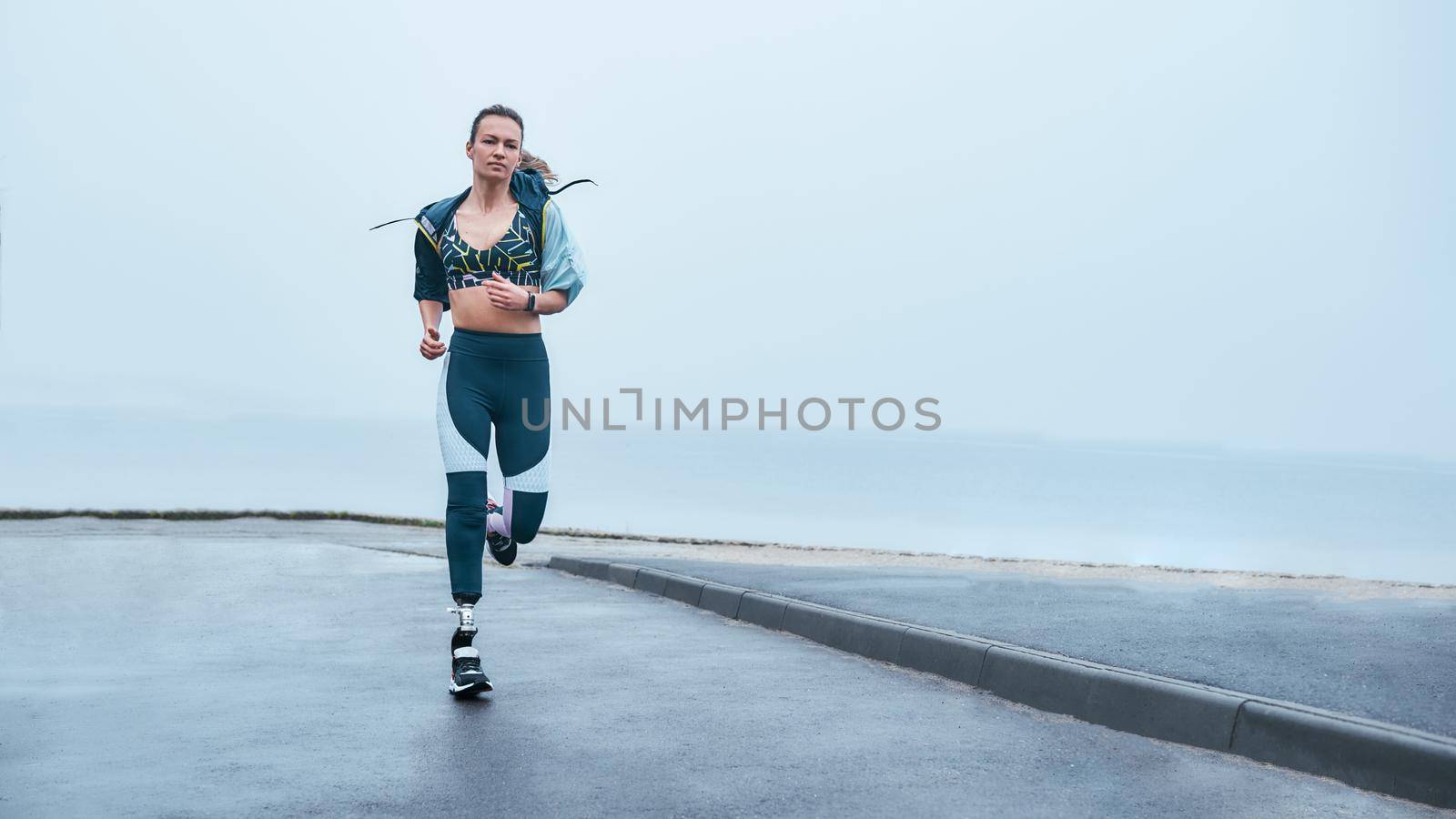 You are stronger than you think. Amazing strong disabled woman in sportswear is running outdoors near the sea by friendsstock