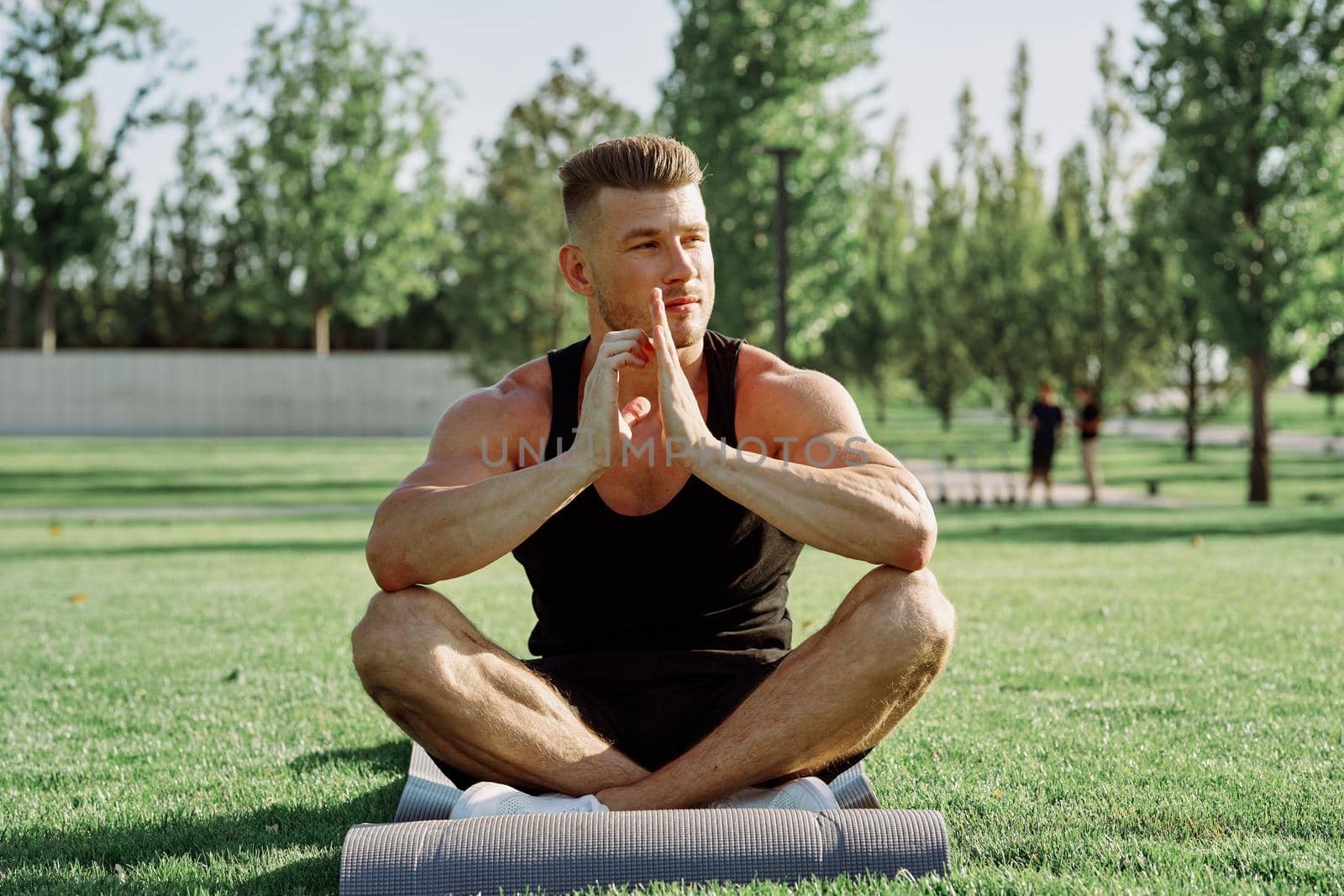 sporty man sitting on the lawn in the park training. High quality photo