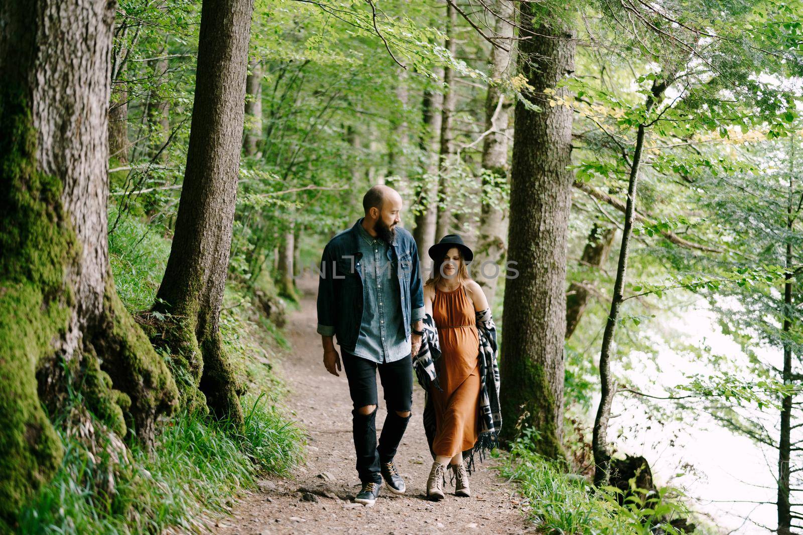 Man and pregnant woman walk along a path. High quality photo