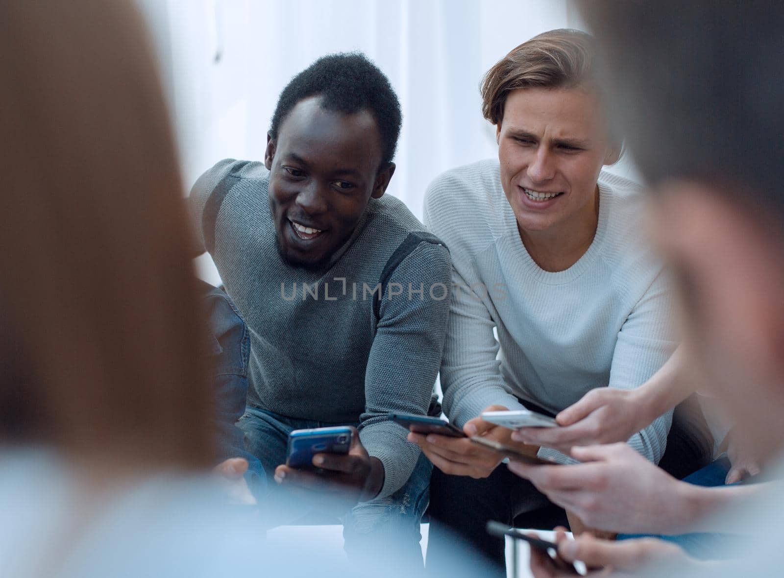 close up. young people with smartphones sitting in a circle by asdf