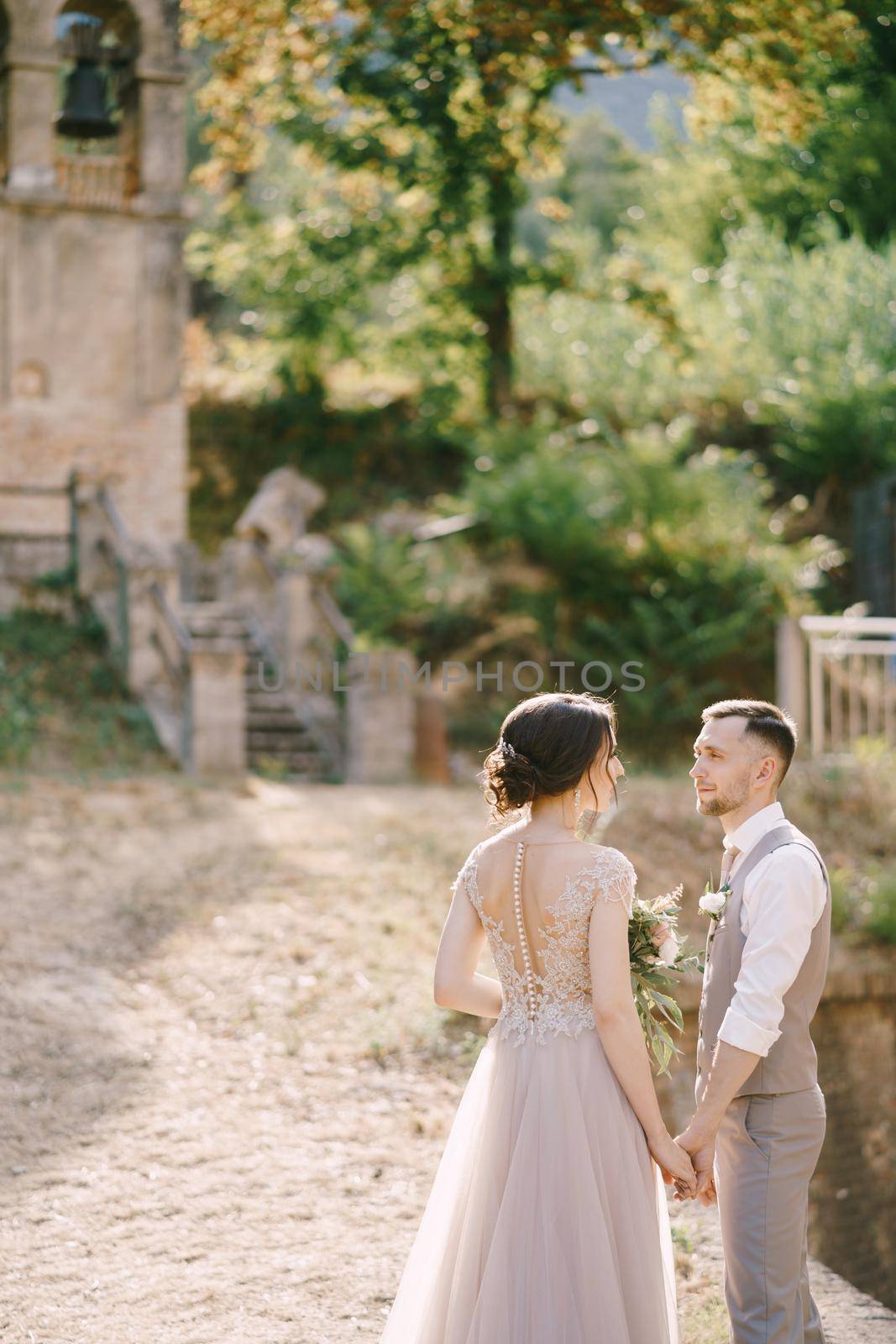Bride and groom stand against the background of a small chapel. High quality photo