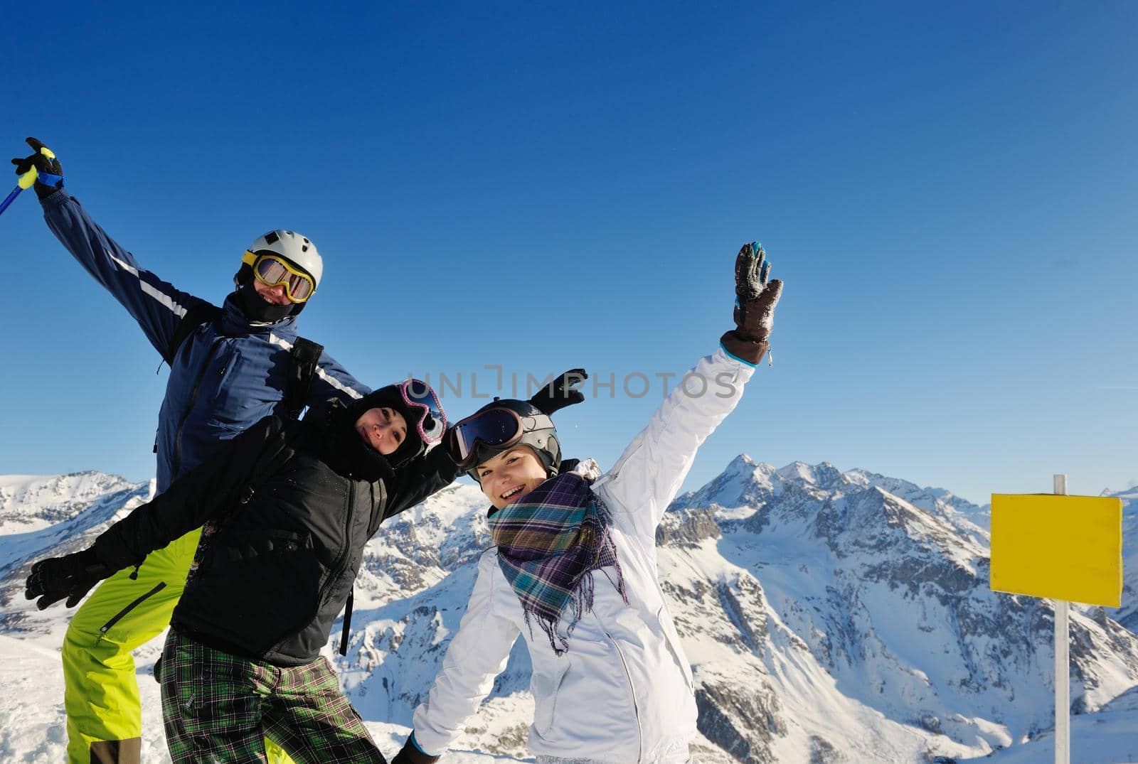 happy people group have fun on ski snow at winter season on mountain with blue sky and fresh air