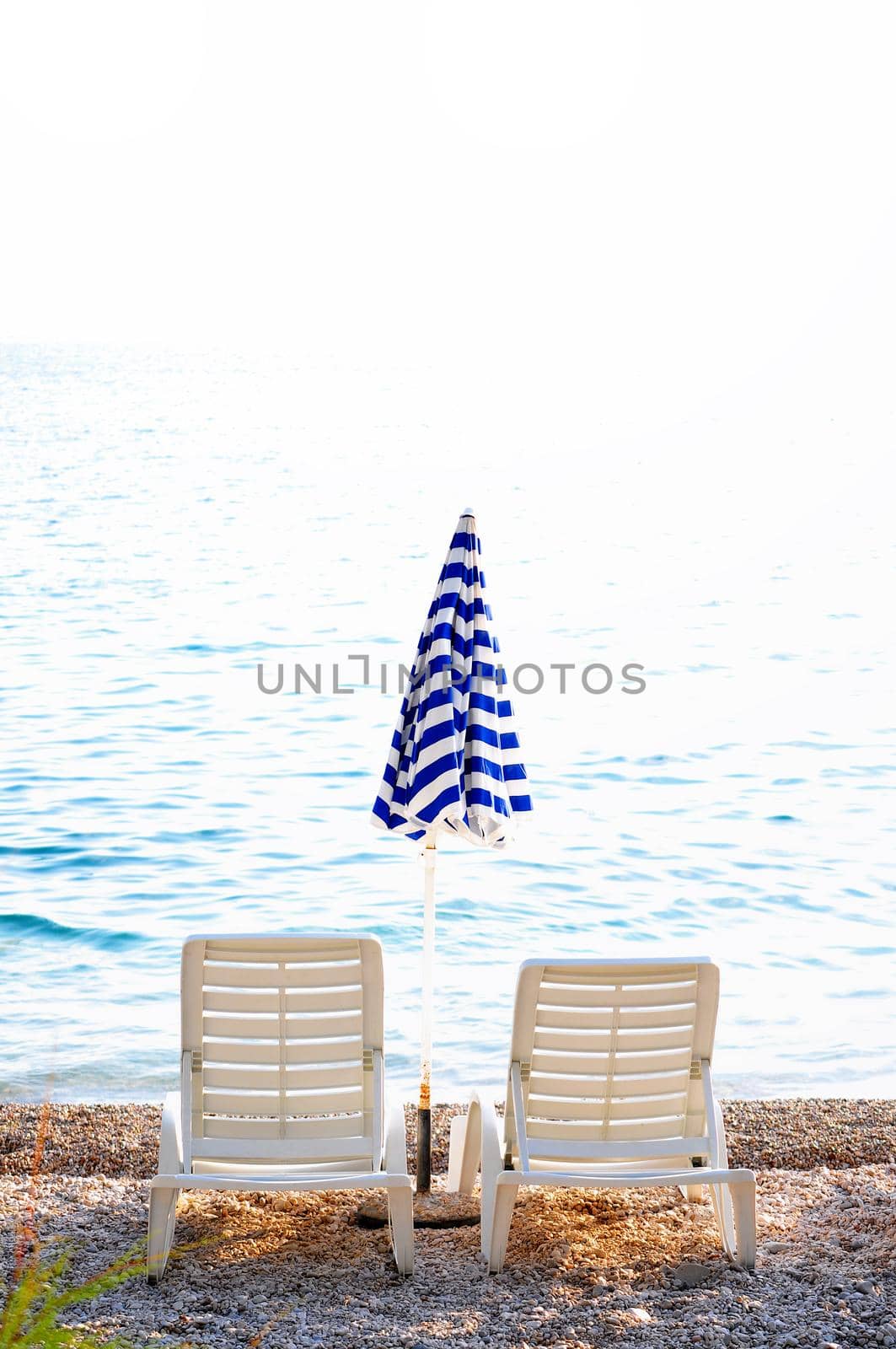 empty chairs on beach with umbrella by dotshock