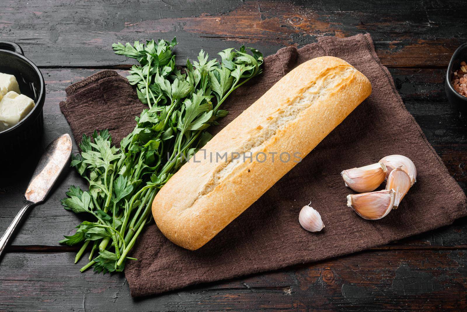 Ingredients for sandwich with butter, herbs and baguette set, on old dark wooden table background