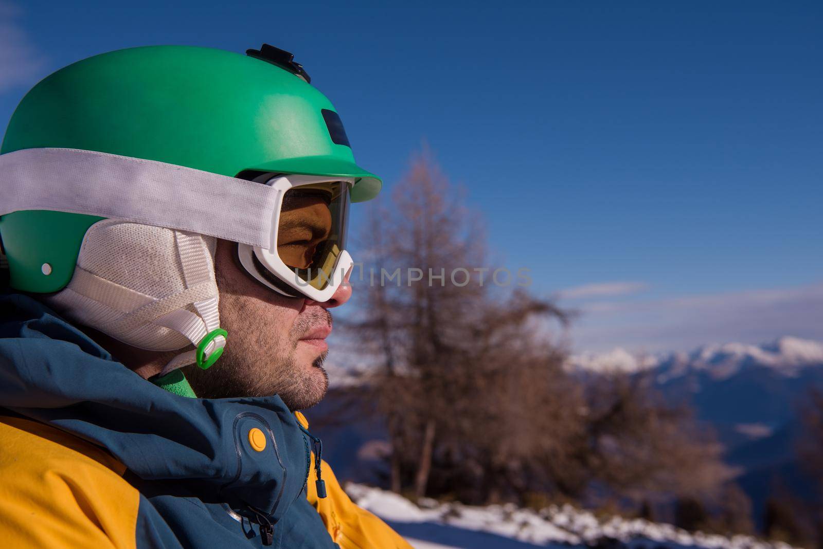 snowboarder relaxing and posing at sunny day on winter season with blue sky in background