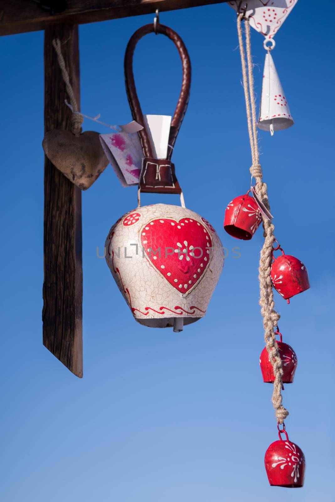 traditional cow bells as home decoration or gift hanging on a wooden beam with blue sky in background