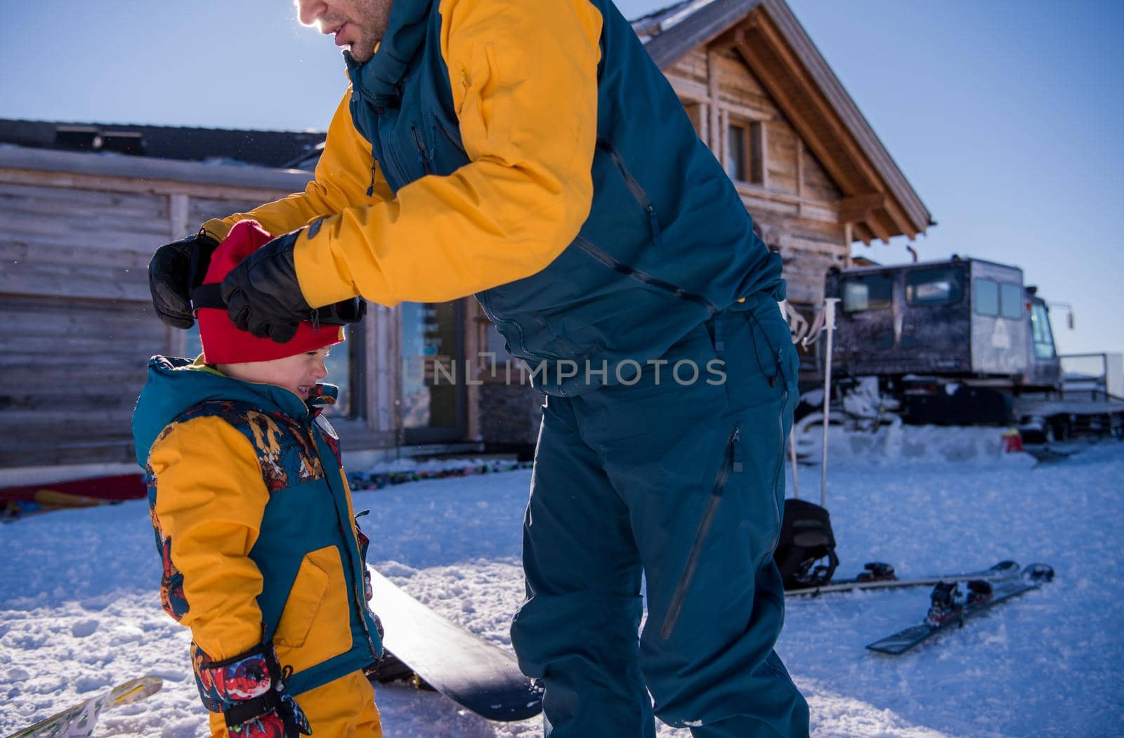 father preparing his little son for the first time on a snowboard by dotshock