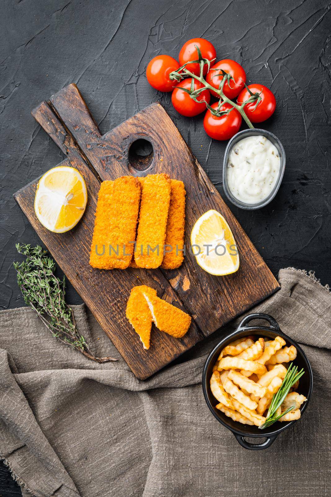 Fried fish finger stick or french fries fish with sauce set, on wooden cutting board, on black background, top view flat lay