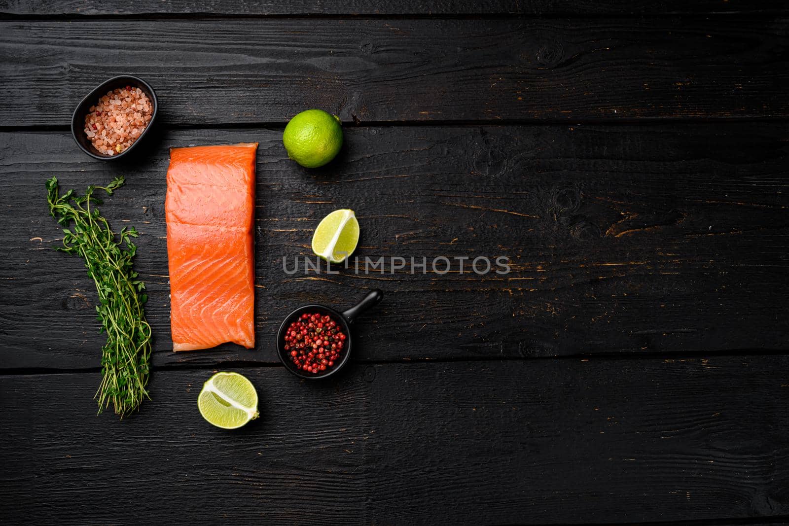 Raw Fillet of salmon set, with herbs, on black wooden table background, top view flat lay, with copy space for text