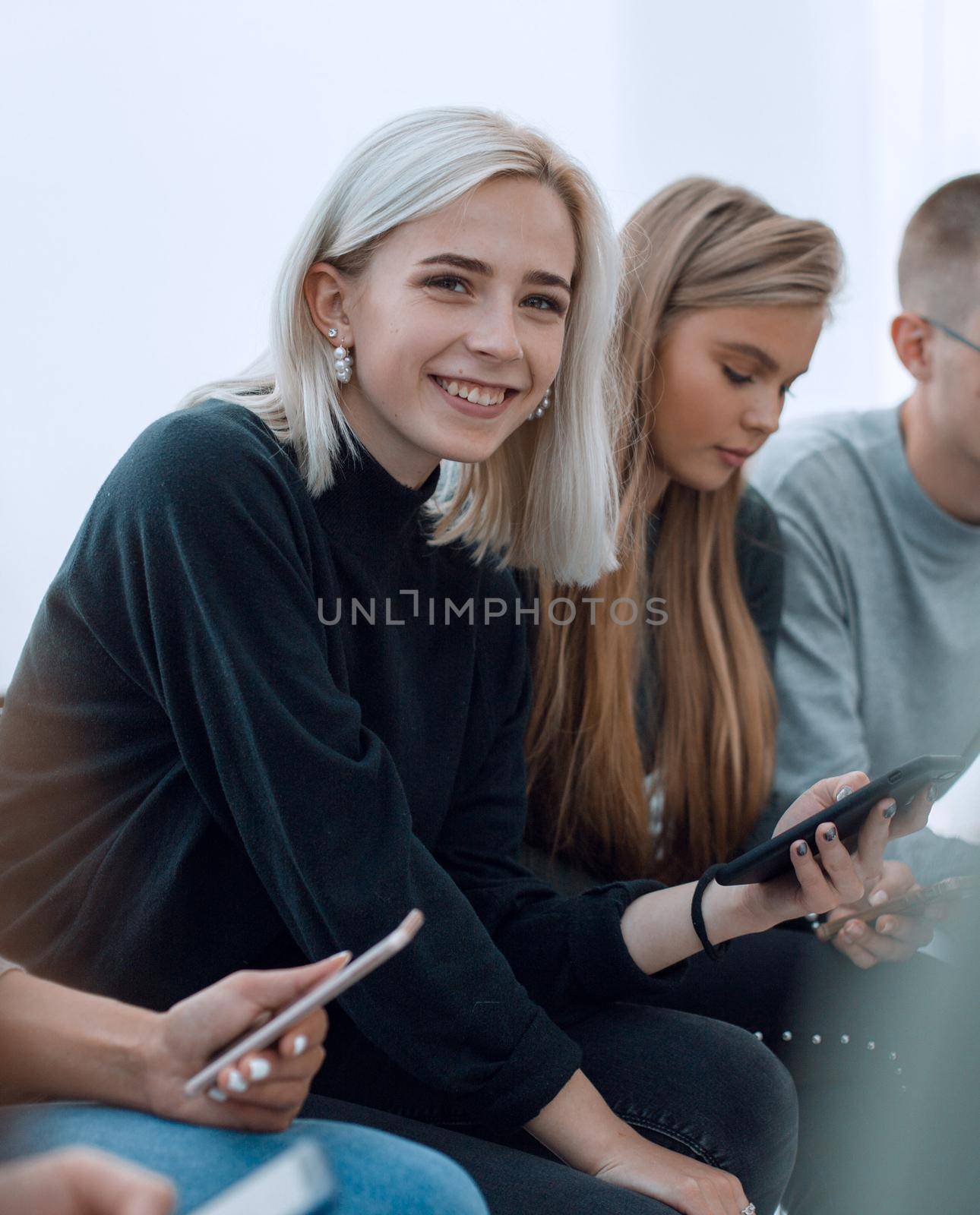 close up. woman with smartphone sitting among her friends by asdf