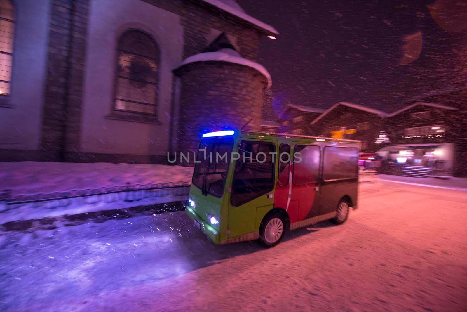 Electric taxi bus on snowy streets in the car-free Alpine mountain village at cold winter night