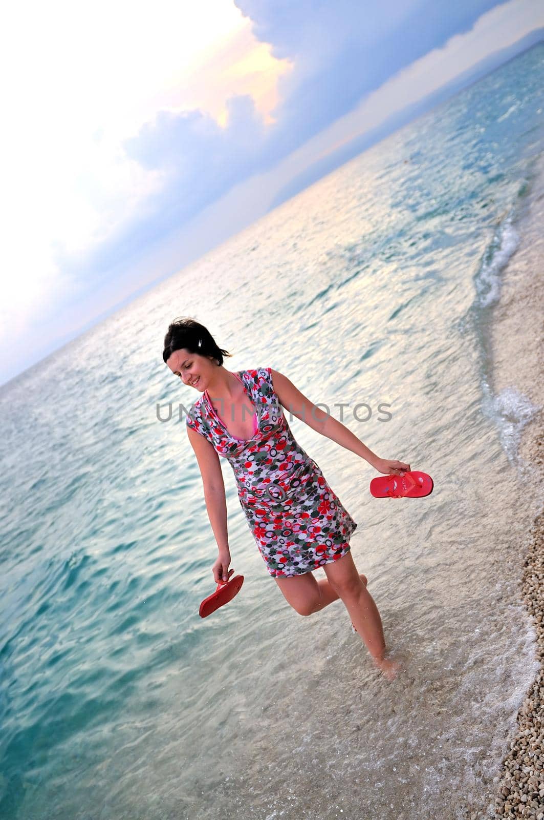 happy and pretty woman alone walking on beach by dotshock