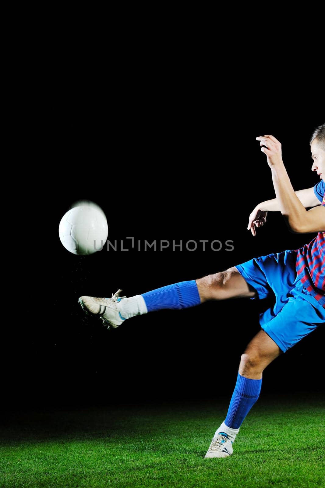 soccer player doing kick with ball on football stadium  field  isolated on black background  in night