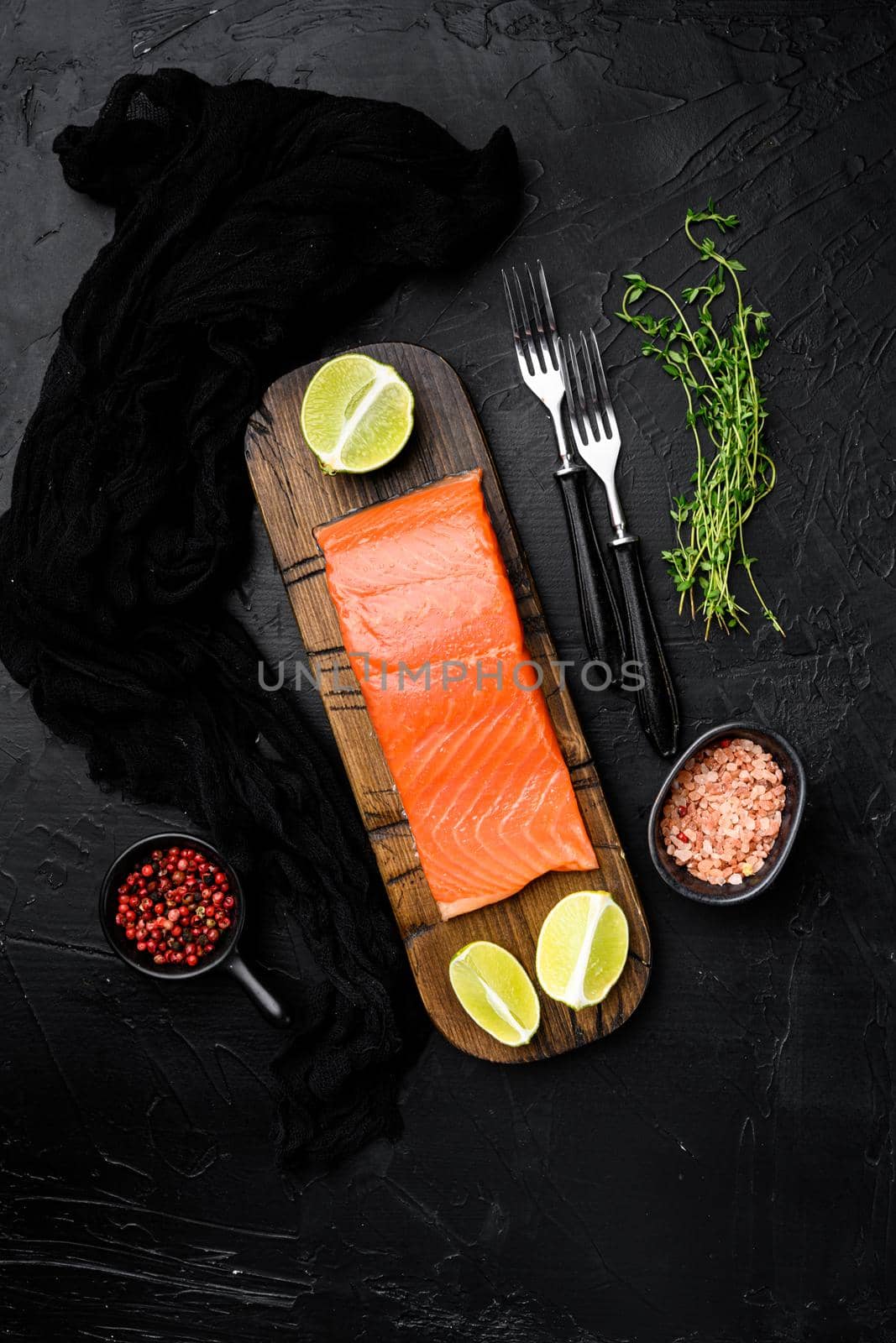 Fillet of salmon or trout set, with herbs, on black dark stone table background, top view flat lay, with copy space for text