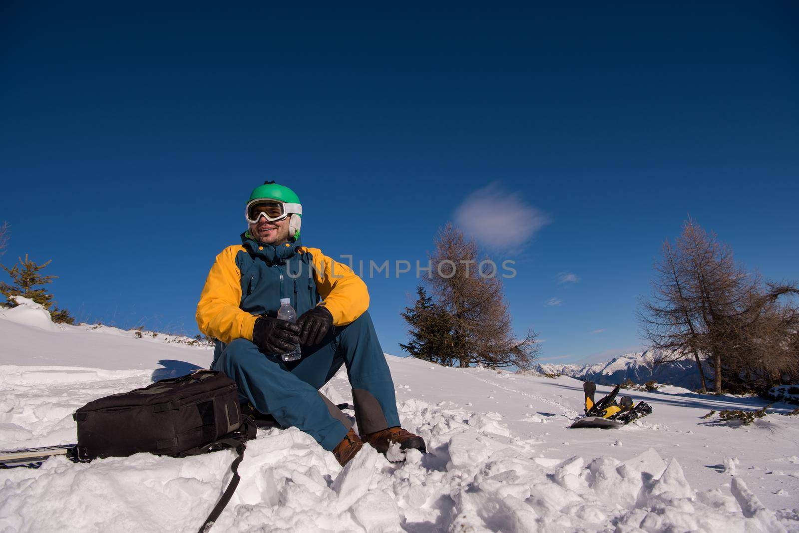 snowboarder relaxing and posing at sunny day on winter season with blue sky in background
