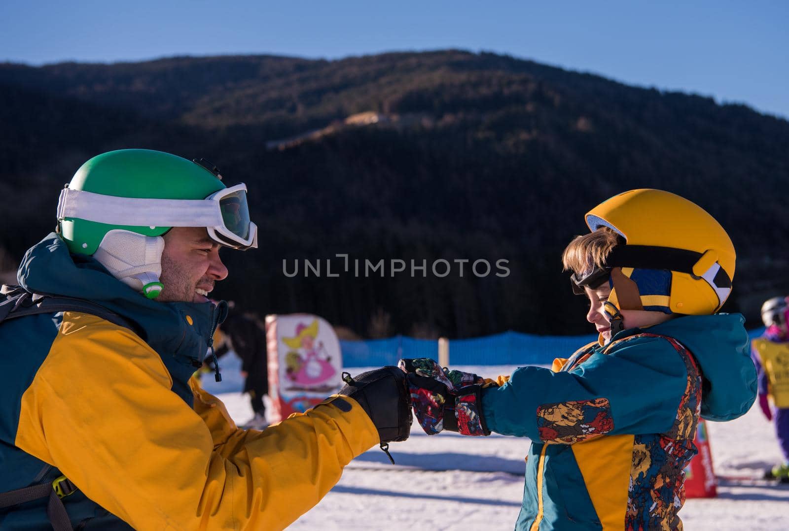 father preparing his little son for the first time on a snowboard by dotshock