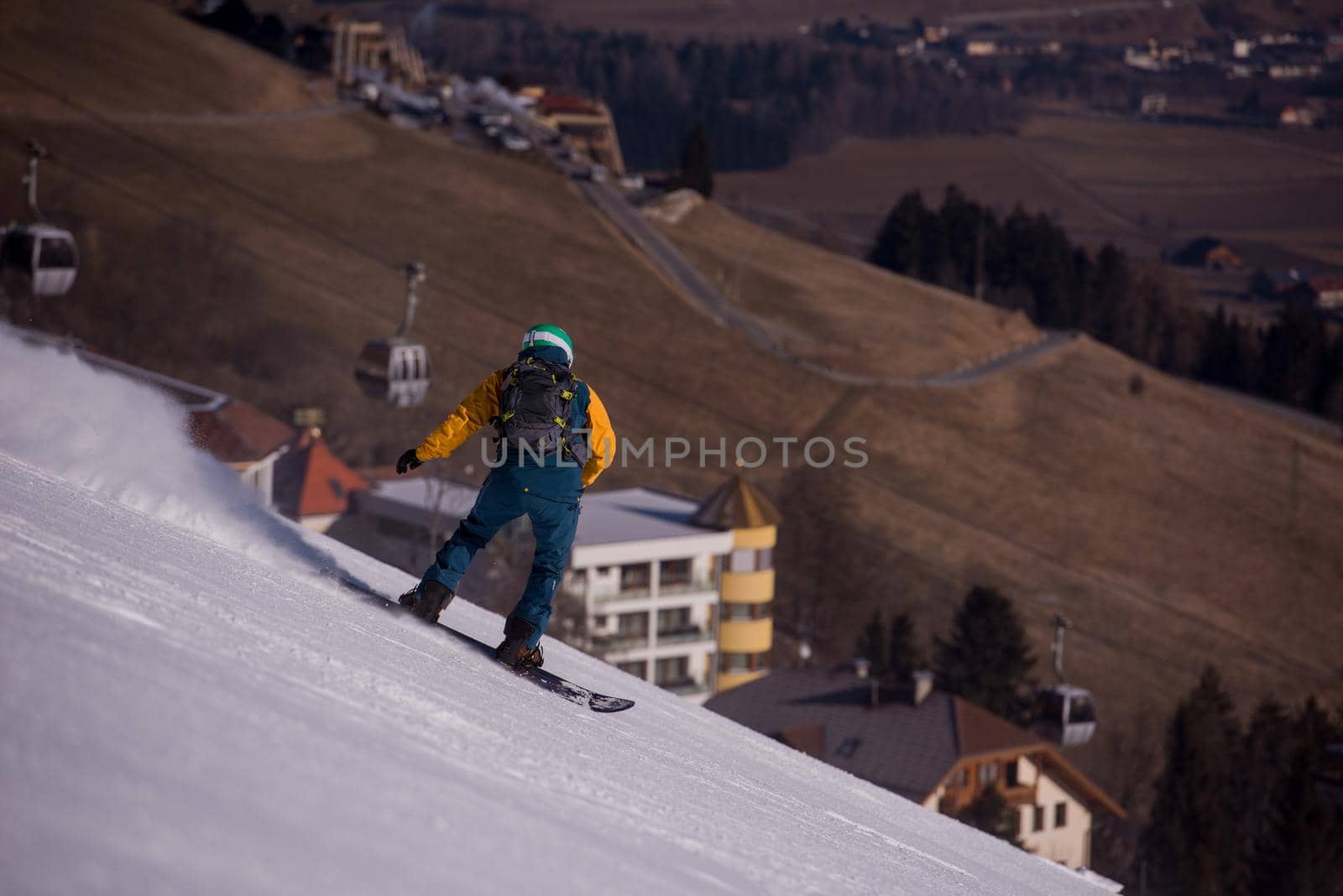 Young freestyle snowboarder running down the slope and ride free style at sunny winter day on Alpine mountains. Winter sport and recreation, leisure outdoor activities.