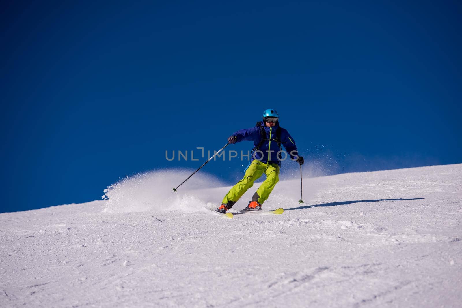 young athlete freestyle Skier having fun while running downhill in beautiful Alpine landscape on sunny day during winter season