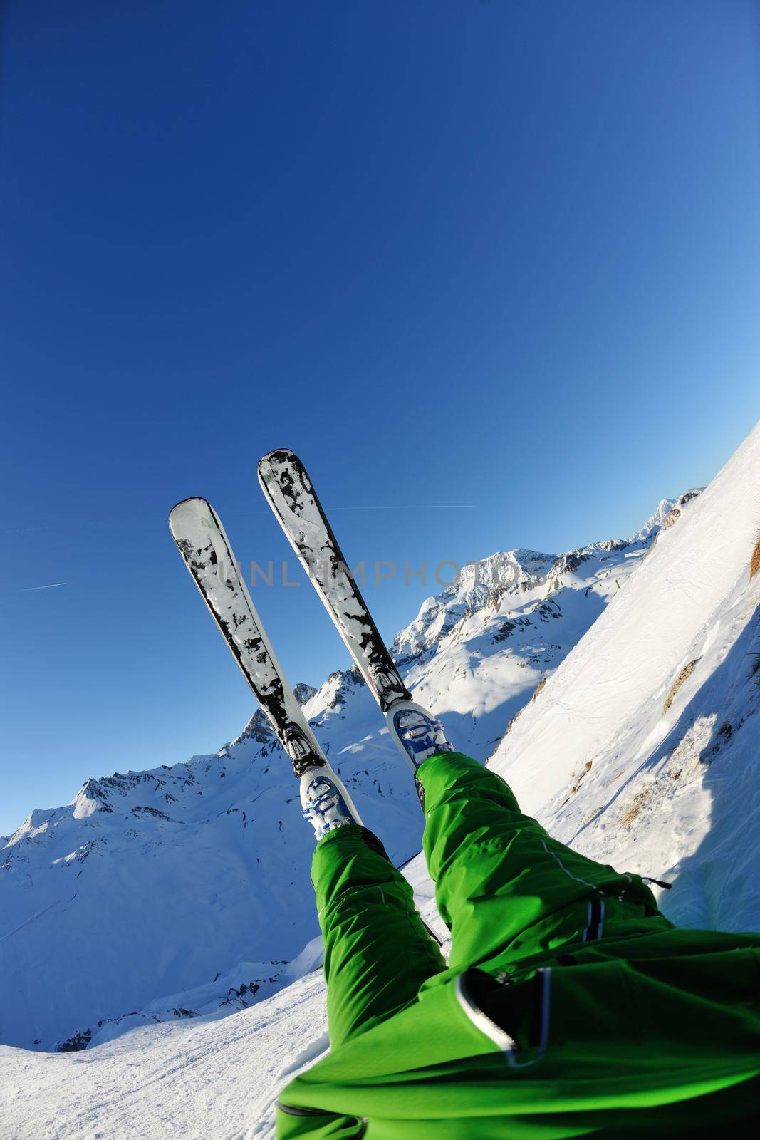 skier skiing downhill on fresh powder snow  with sun and mountains in background