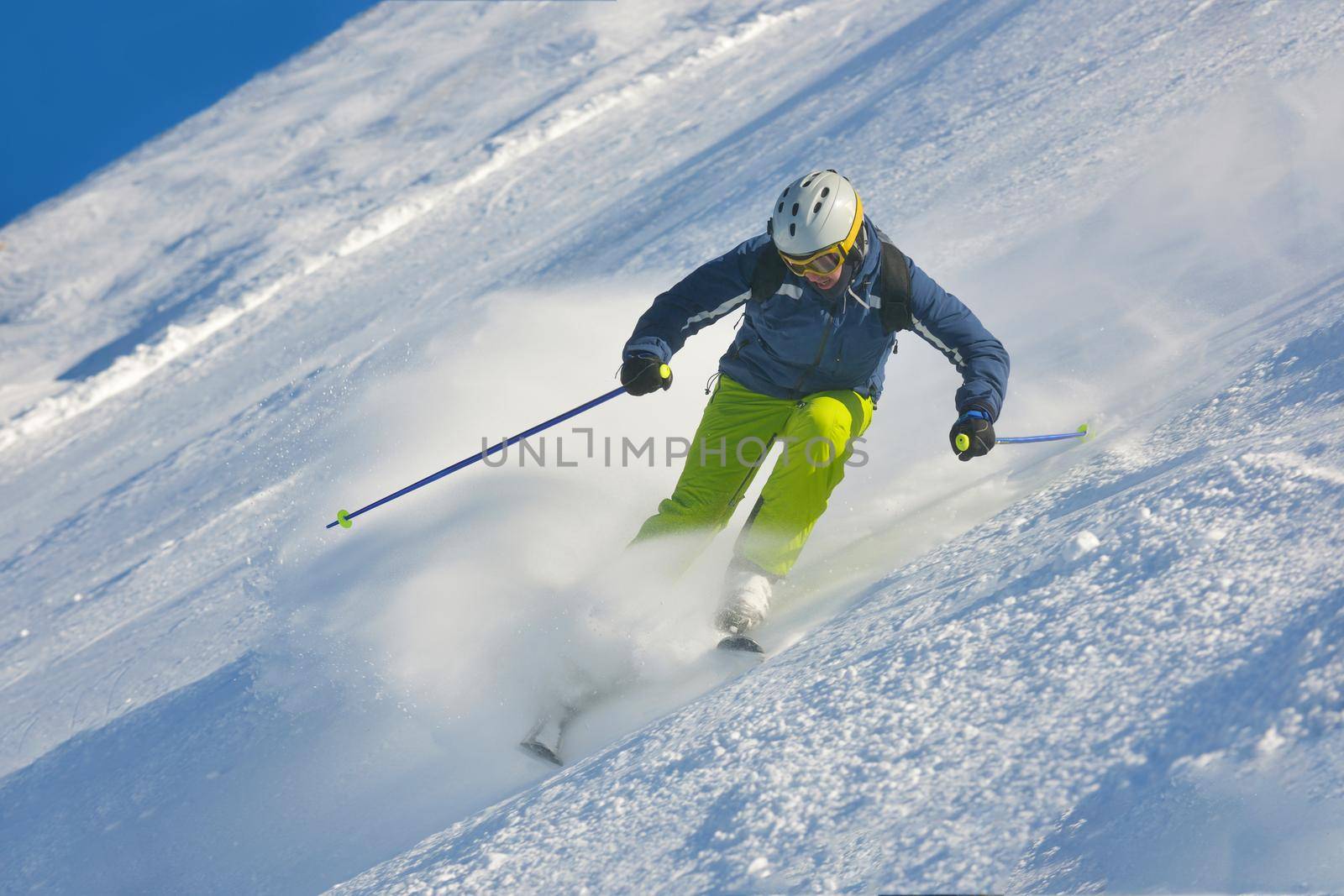 skier skiing downhill on fresh powder snow  with sun and mountains in background