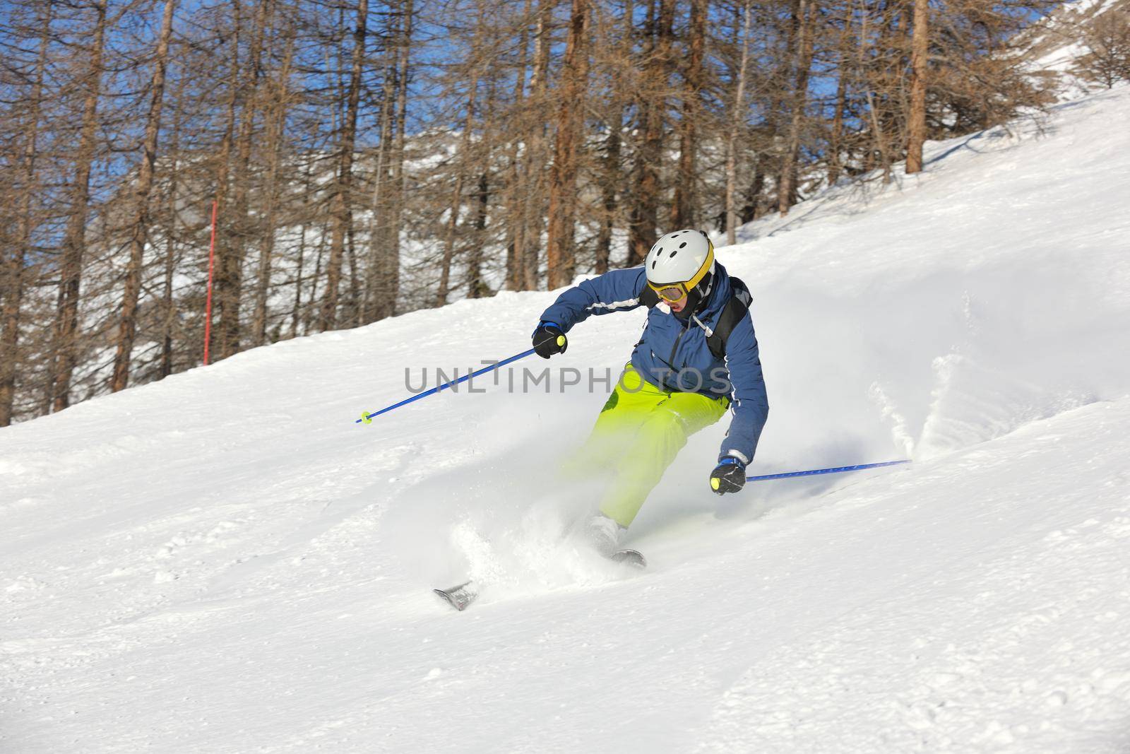 skier skiing downhill on fresh powder snow  with sun and mountains in background