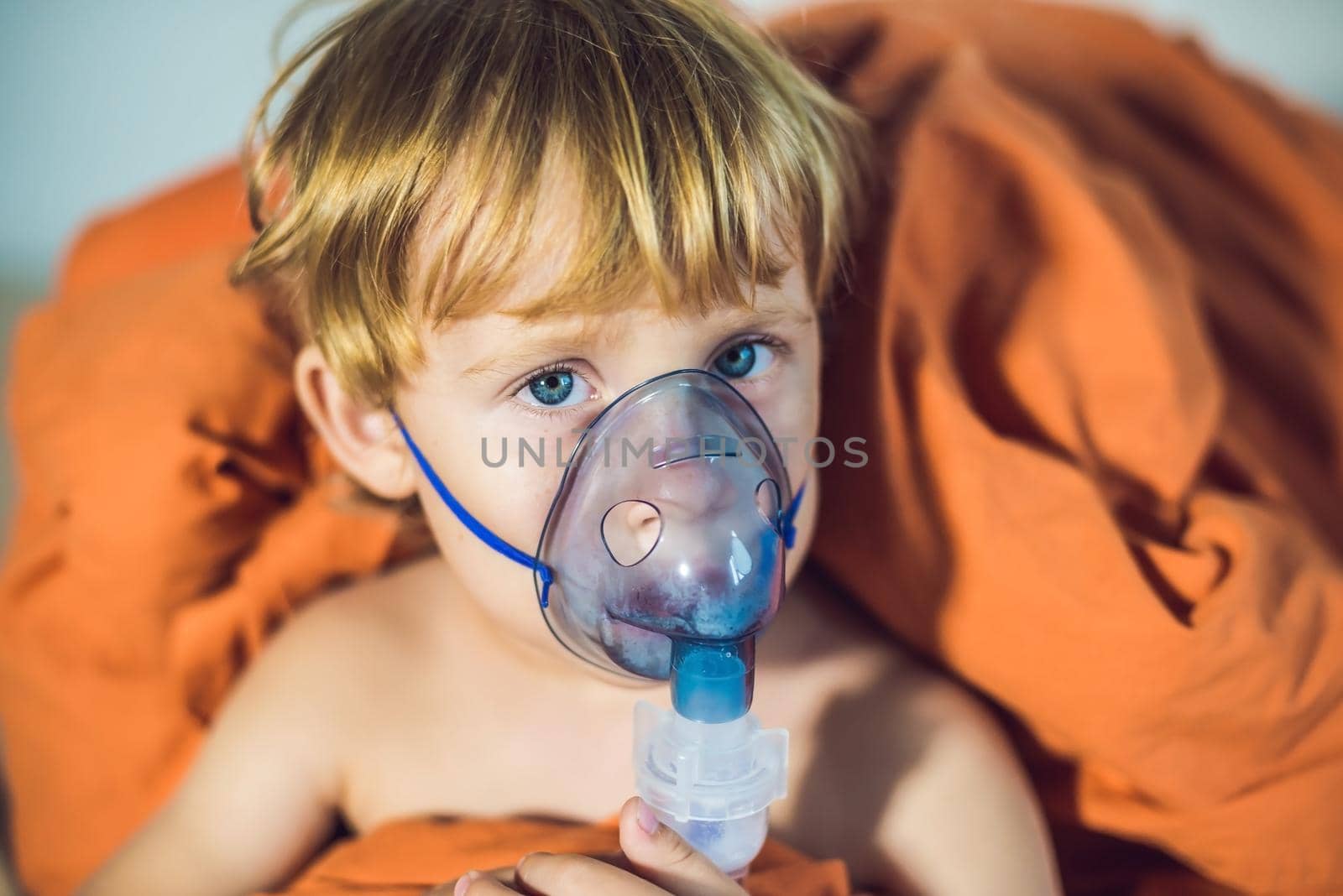 Boy making inhalation with a nebulizer at home.