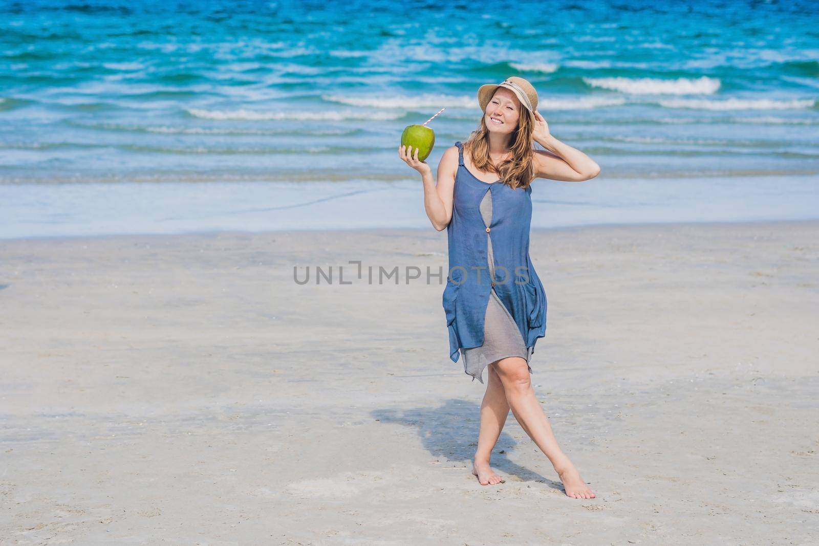 Attractive young woman drinking coconut water on the beach.