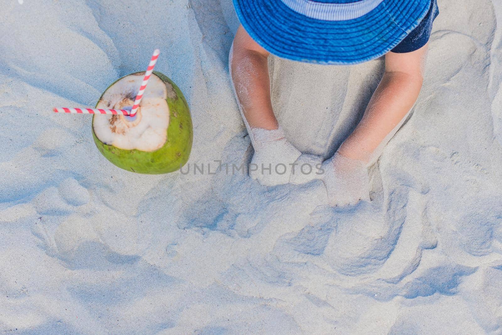 Coconut with straw in the sand on the beach.