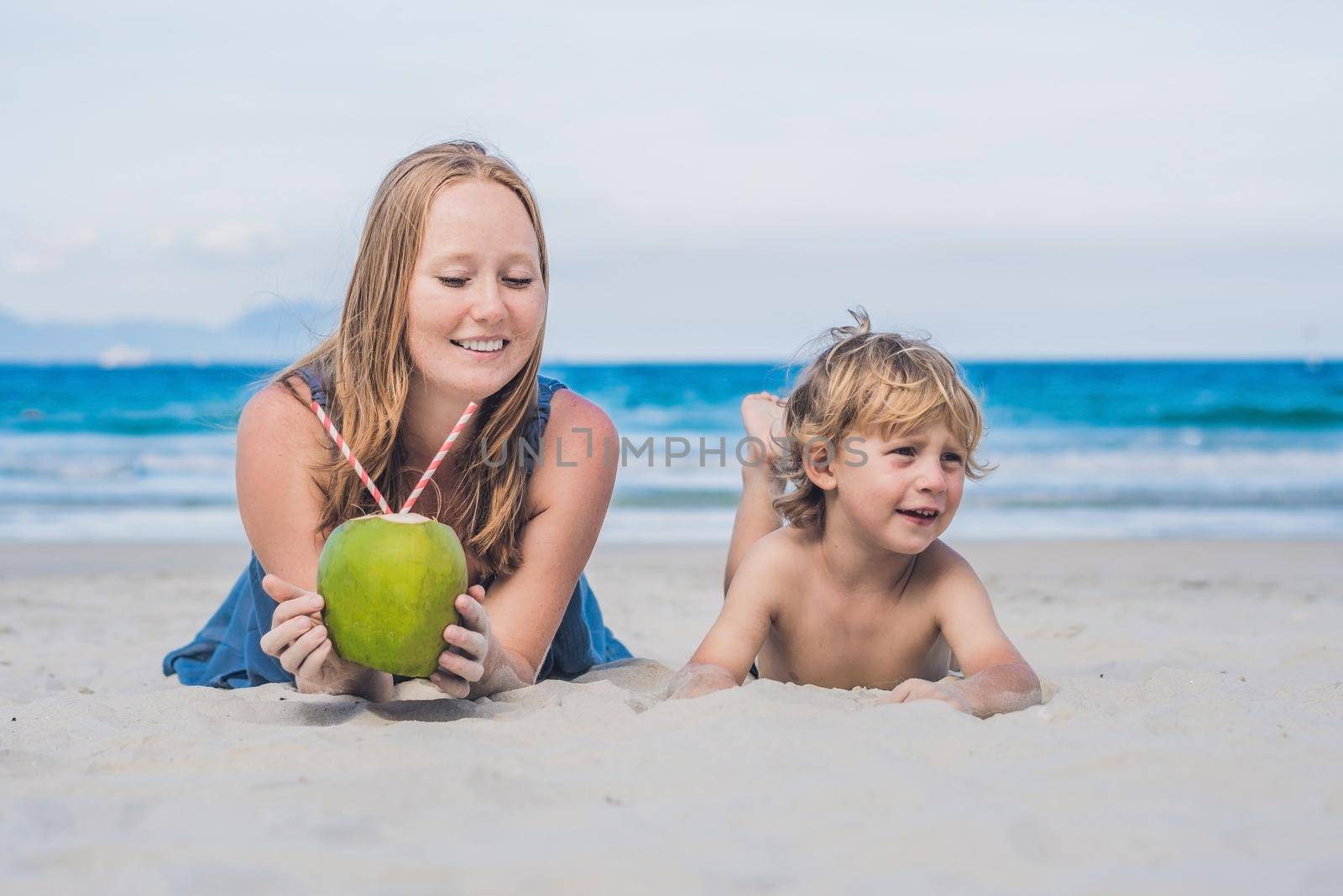 Mom and son enjoy the beach and drink coconut by galitskaya