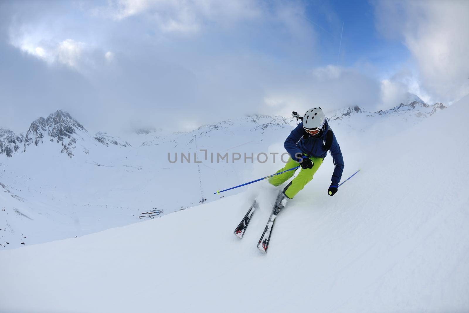 skier skiing downhill on fresh powder snow  with sun and mountains in background