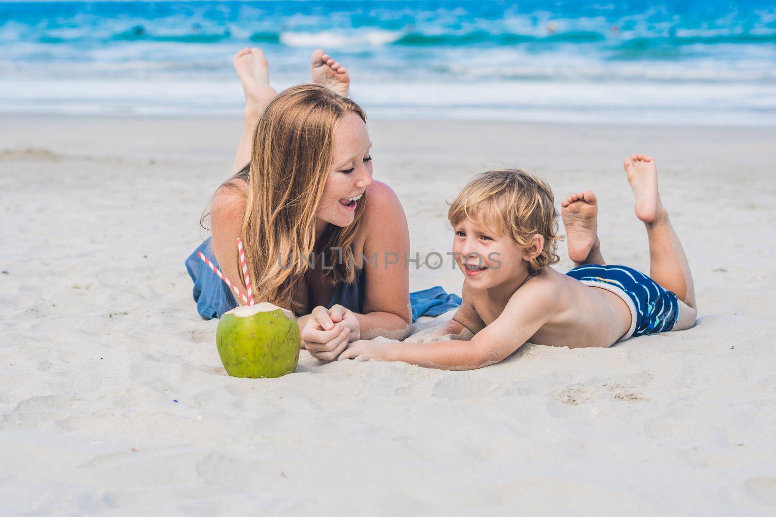 Mom and son enjoy the beach and drink coconut by galitskaya
