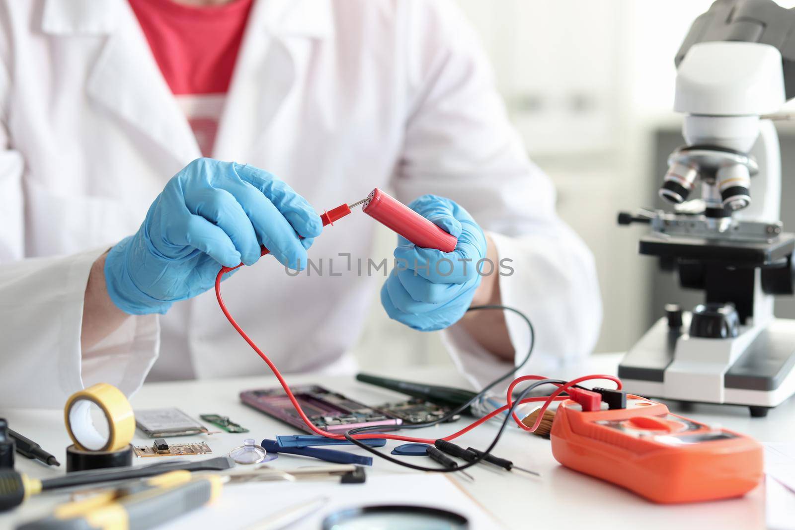 Master repairman checking battery charge using tester closeup. Electronics diagnostics concept