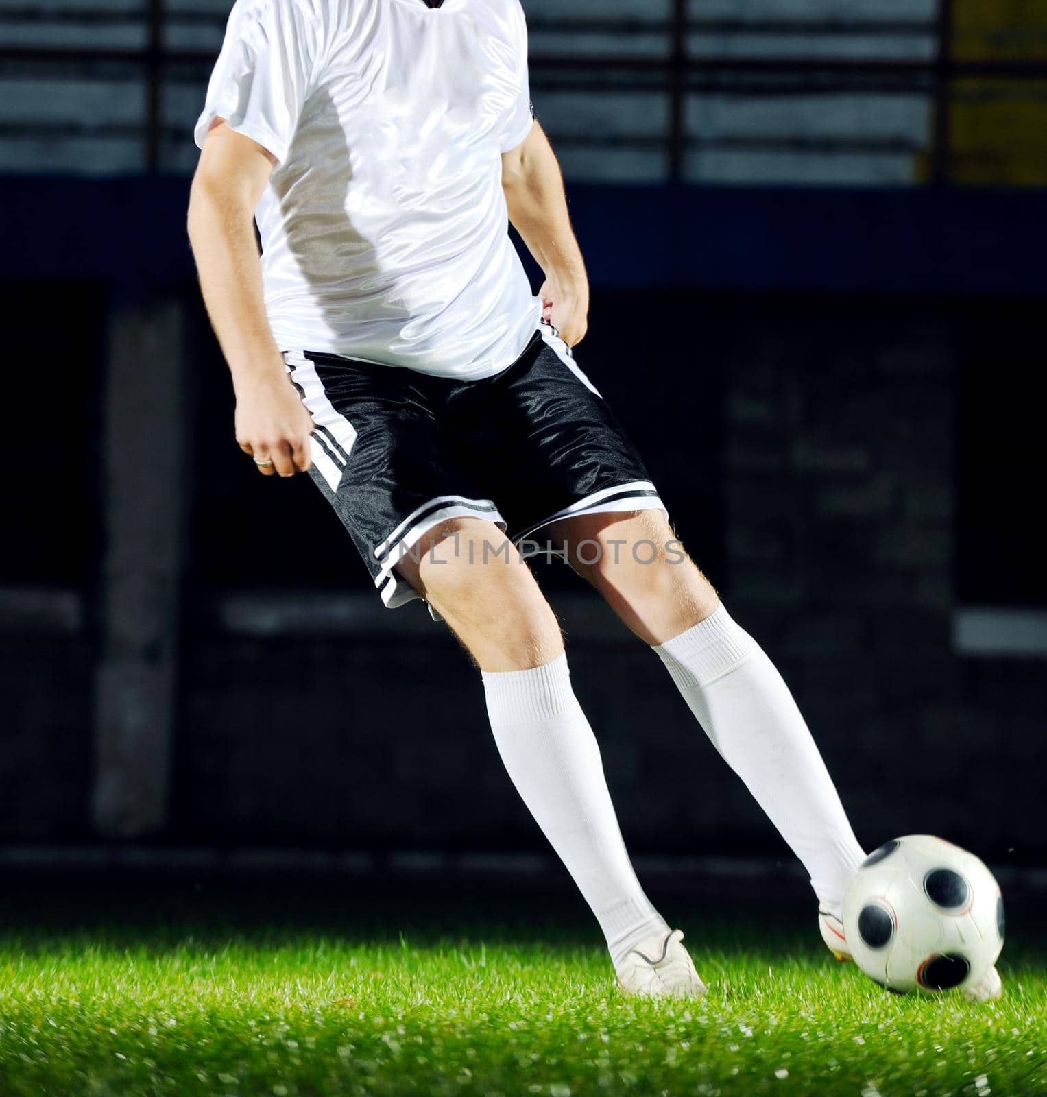 soccer player doing kick with ball on football stadium  field  isolated on black background  in night