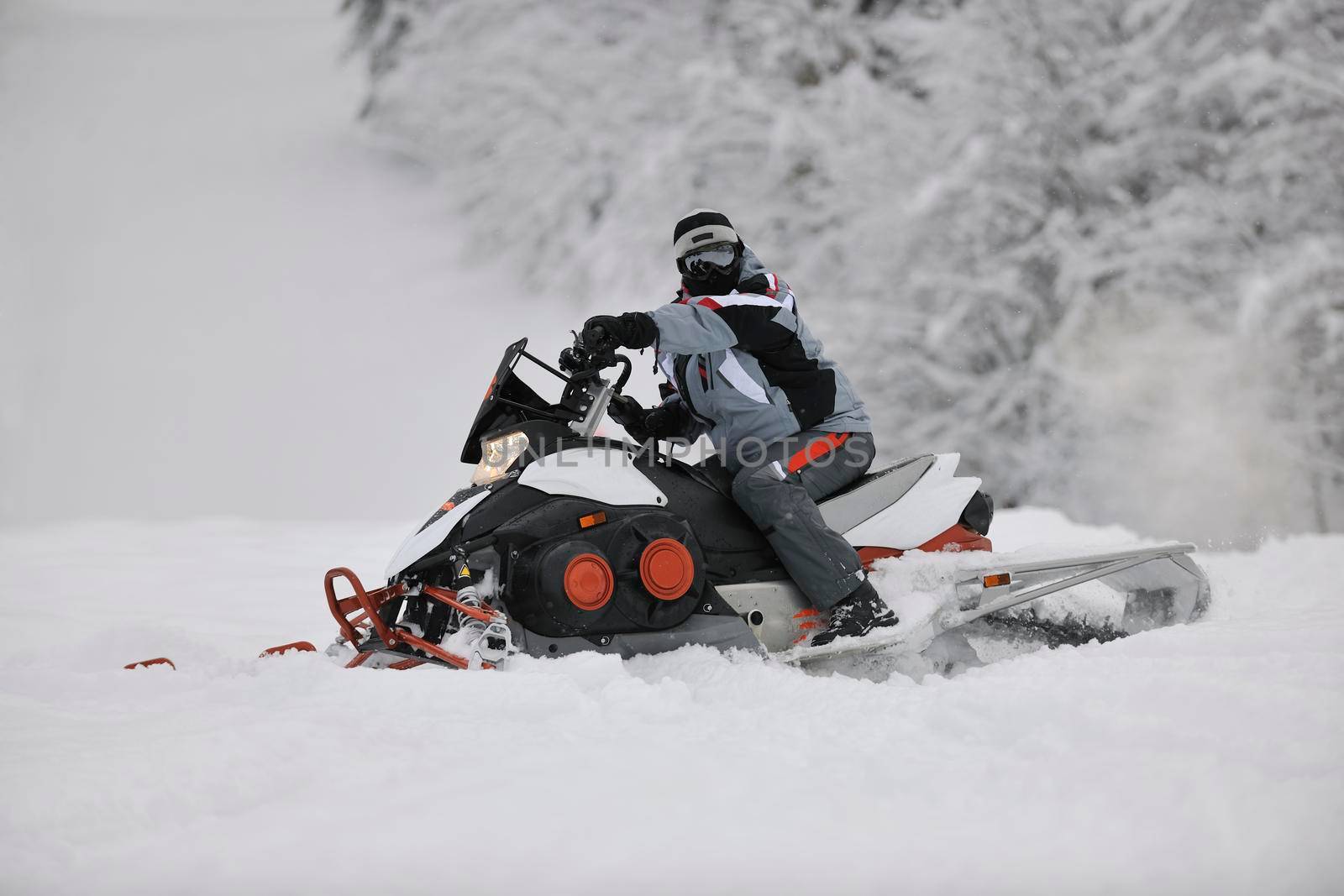 young man posing on snowmobile at beautiful winter day