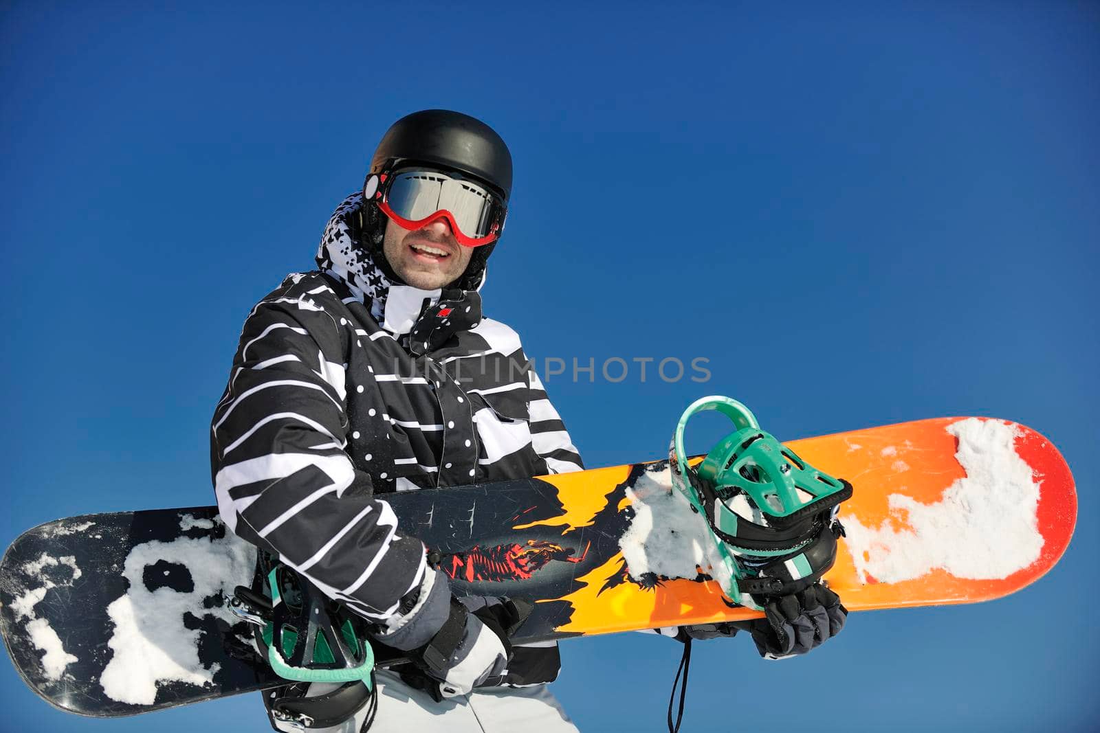 snowboarder relaxing and posing at sunny day on winter season with blue sky in background