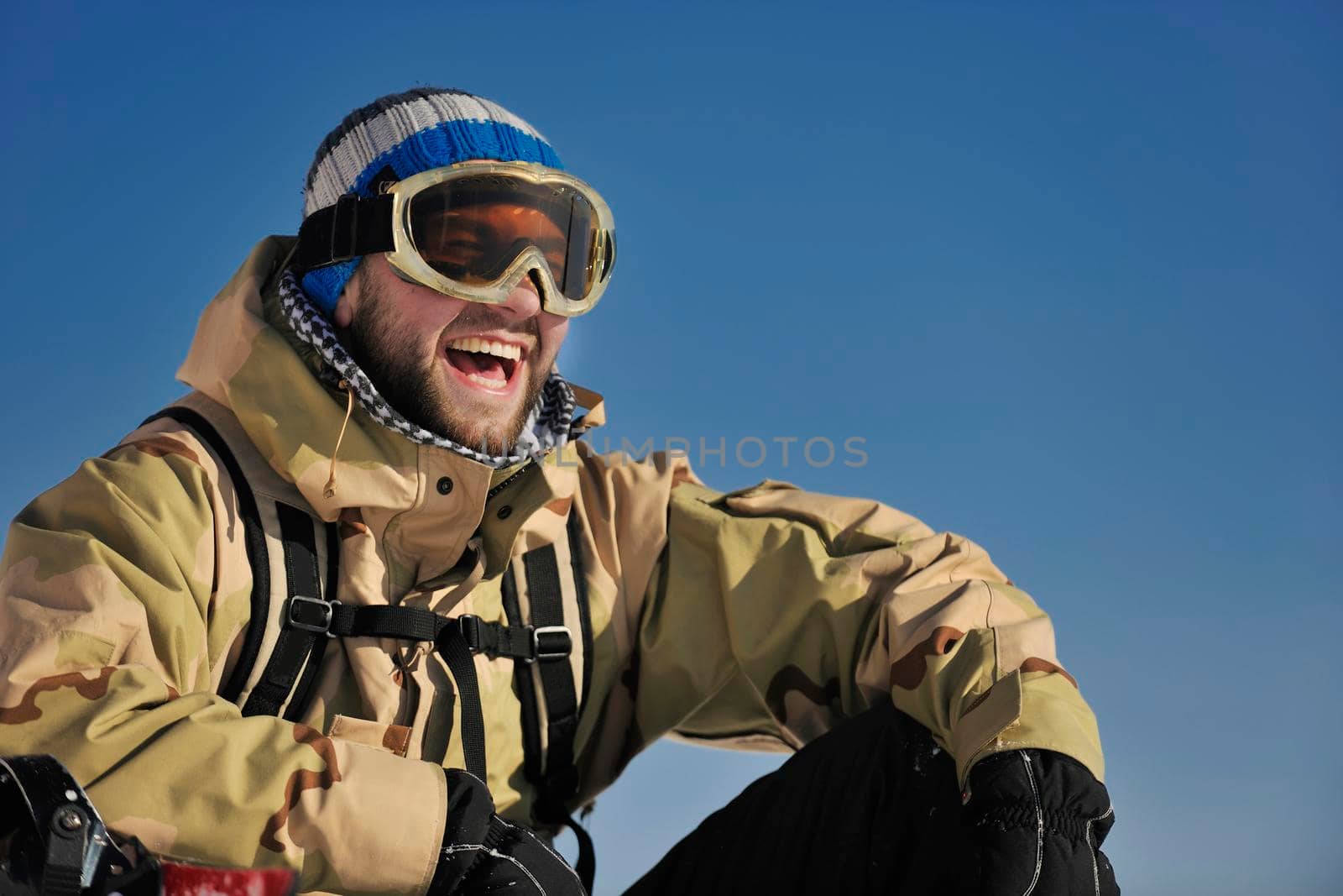 snowboarder relaxing and posing at sunny day on winter season with blue sky in background